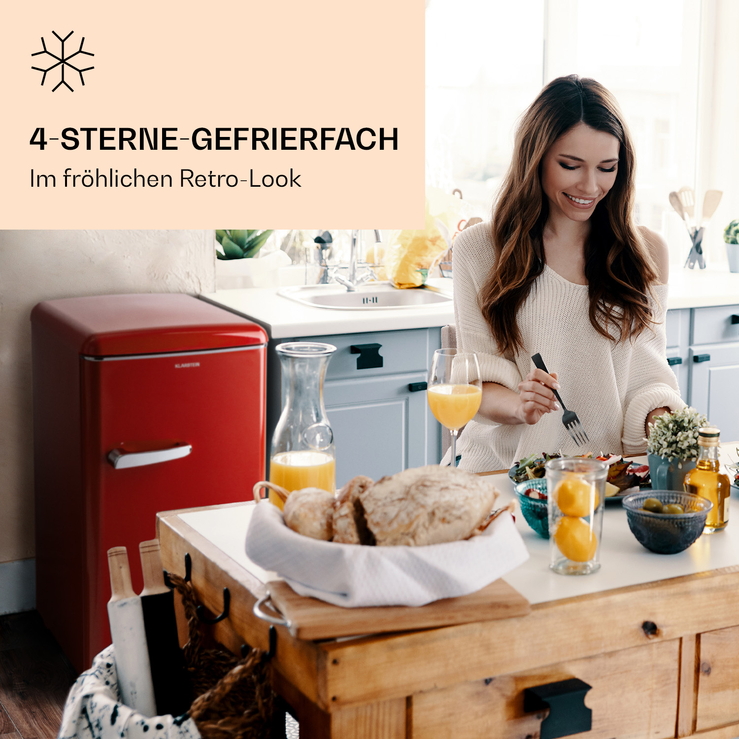 Eine Frau isst an einem Tisch mit Essen und einem roten Retro-Kühlschrank im Hintergrund.