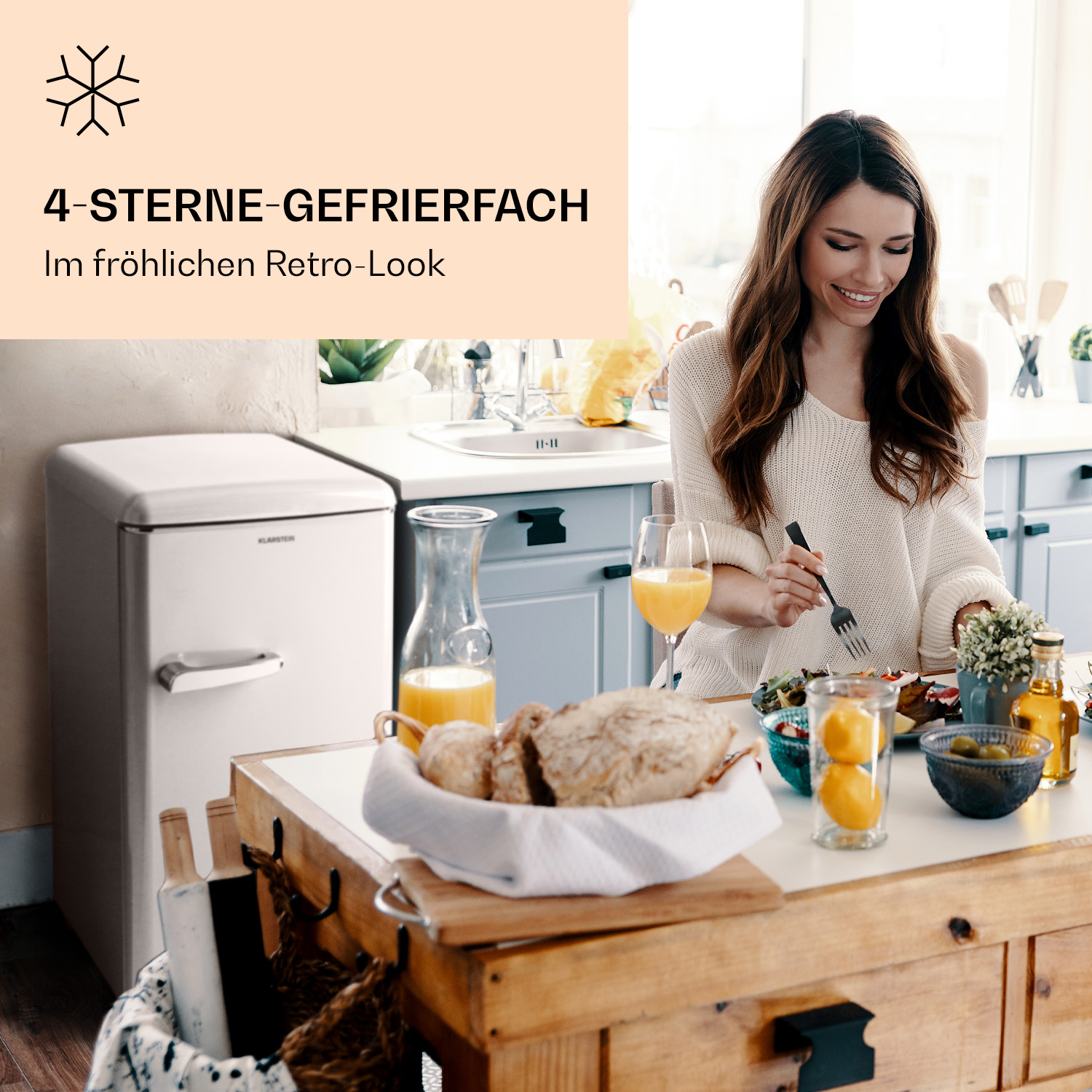 Una donna a tavola con cibo e un frigorifero in stile retrò sullo sfondo.