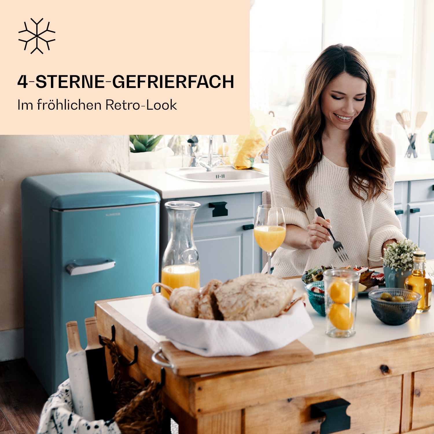 Frau isst an einem Tisch mit einem blauen Retro-Kühlschrank im Hintergrund.