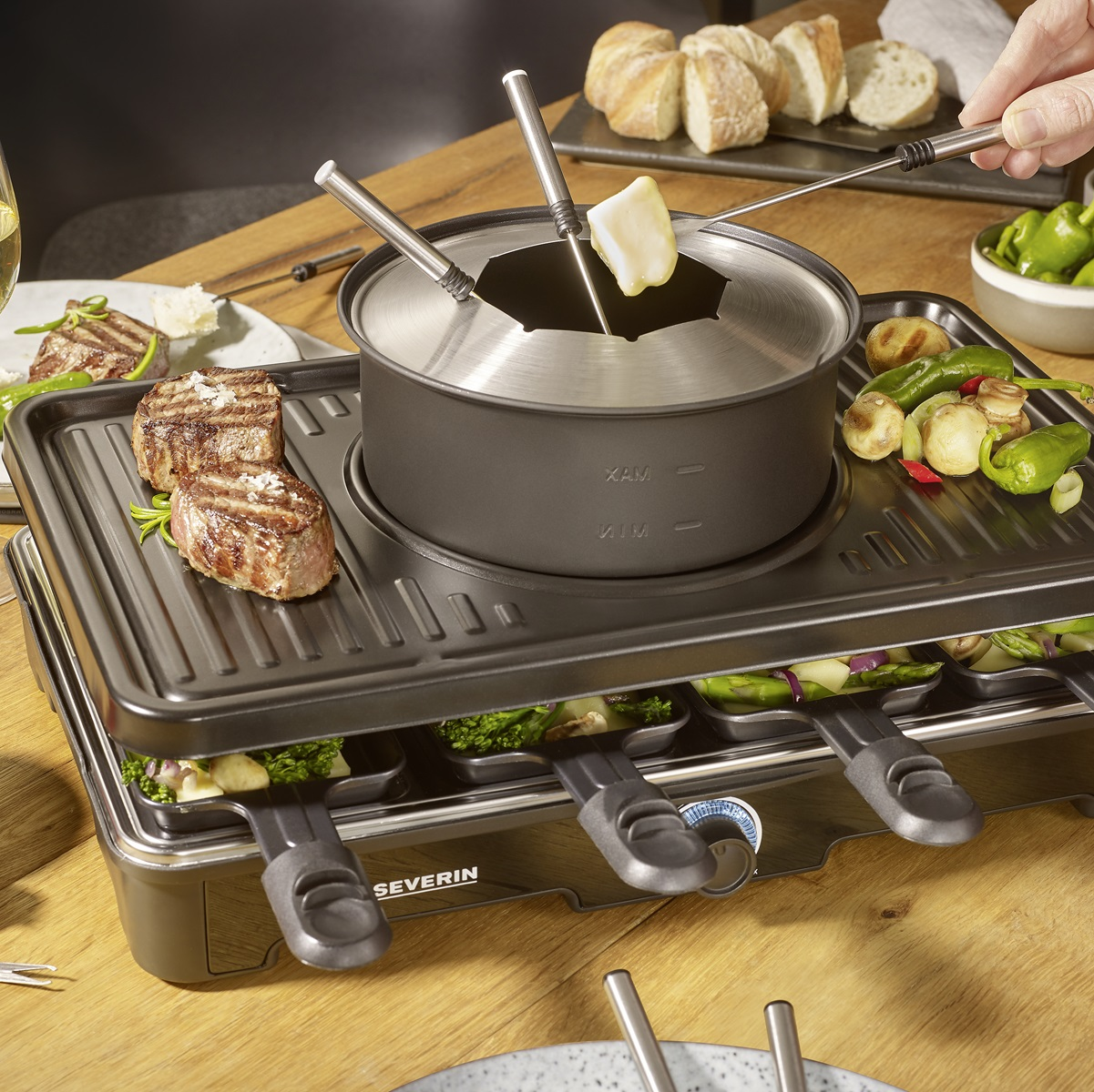 Zestaw do raclette z gotowym jedzeniem i garnkiem do fondue, sięgające ręce.