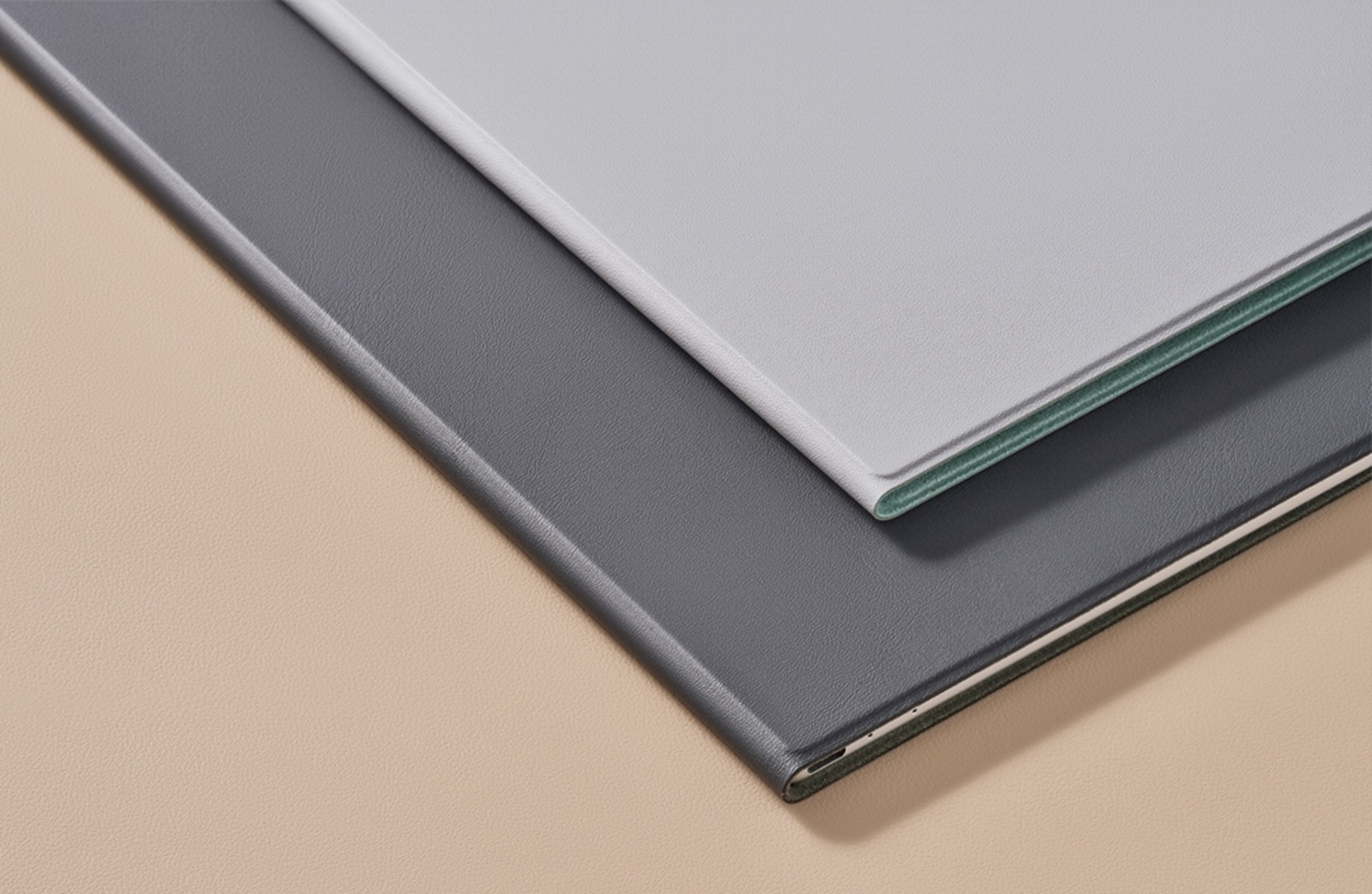Dos libros o blocs grises y gris claro, primer plano sobre una superficie beige.