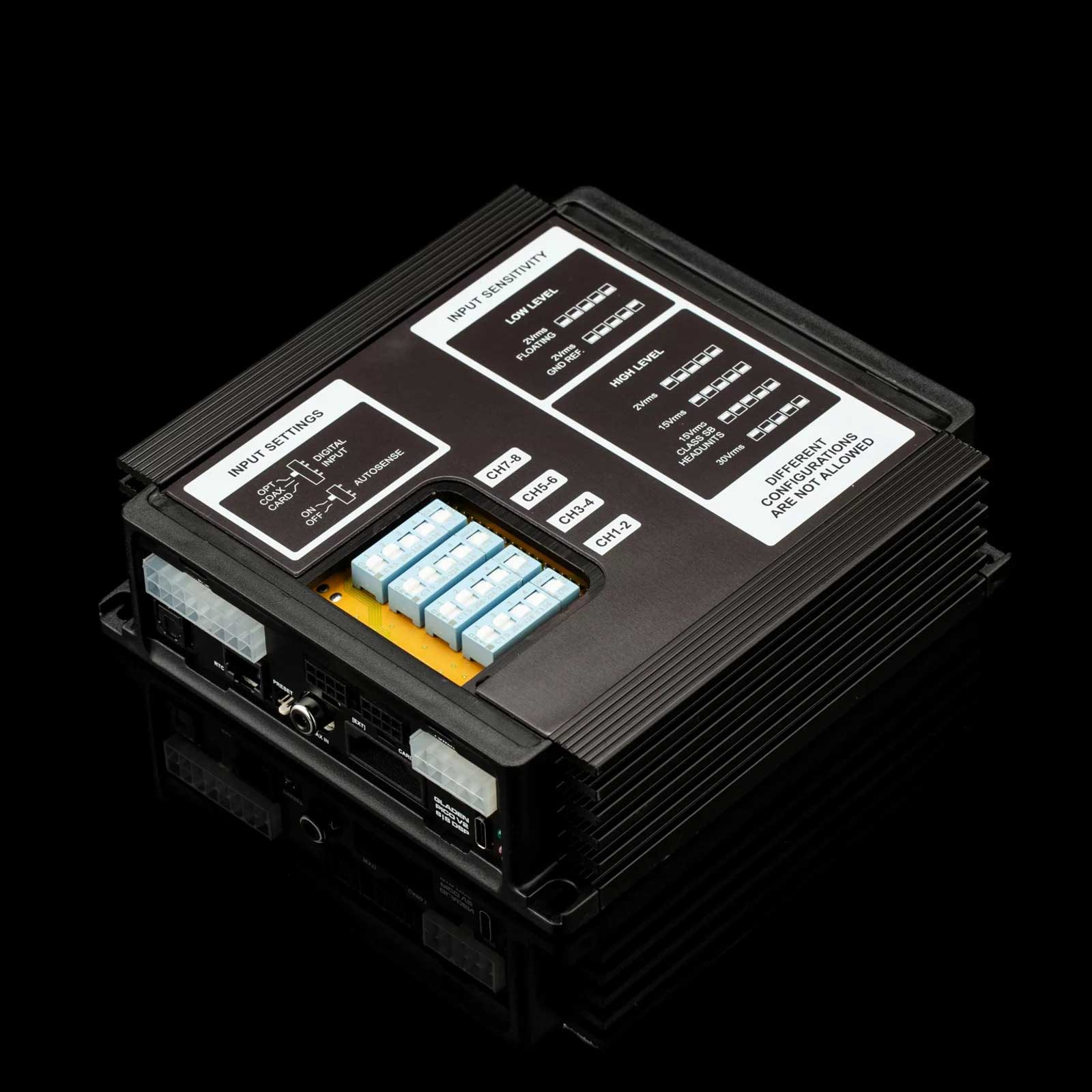 Schwarzes elektronisches Gerät mit beschrifteten Eingängen. Es hat mehrere Anschlüsse und Knöpfe. Das Gerät steht auf einer schwarzen Oberfläche.