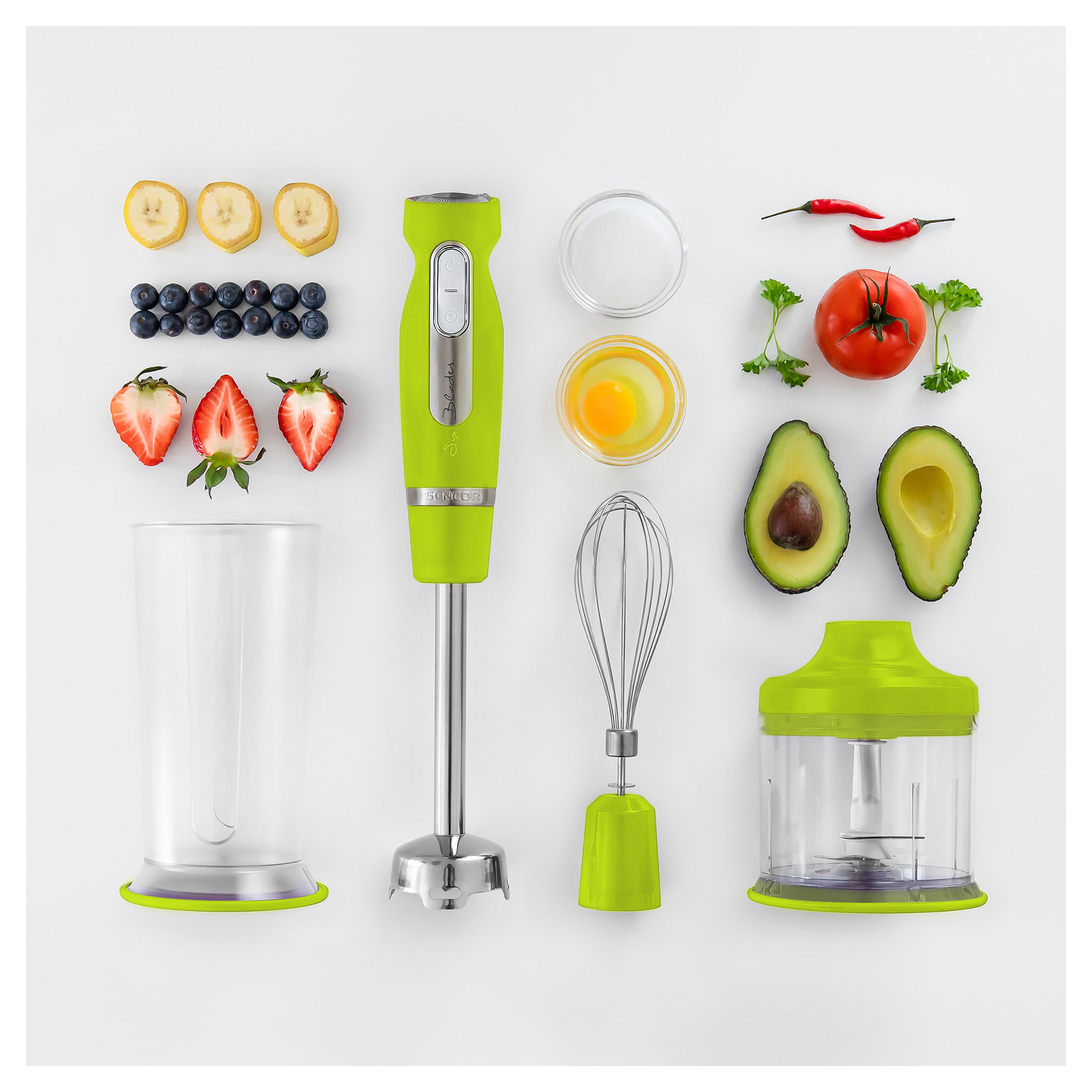 Frullatore verde con frutta e verdura disposte su una superficie bianca.