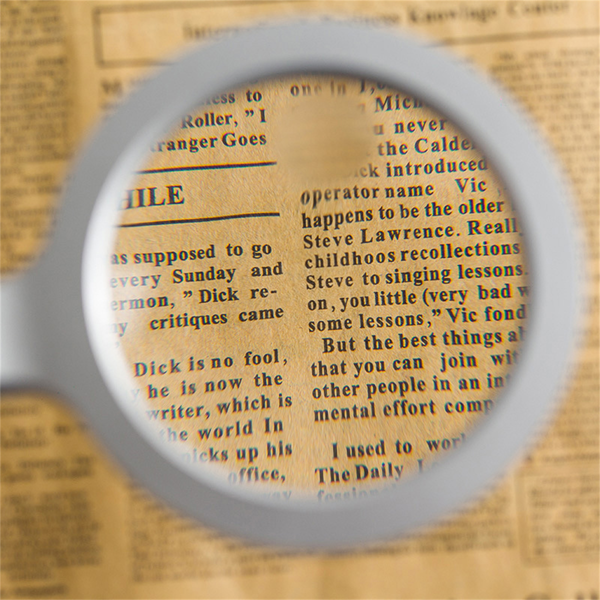Lupe über einer Zeitung. Der Text ist scharf gestellt. Das Papier ist vergilbt.
