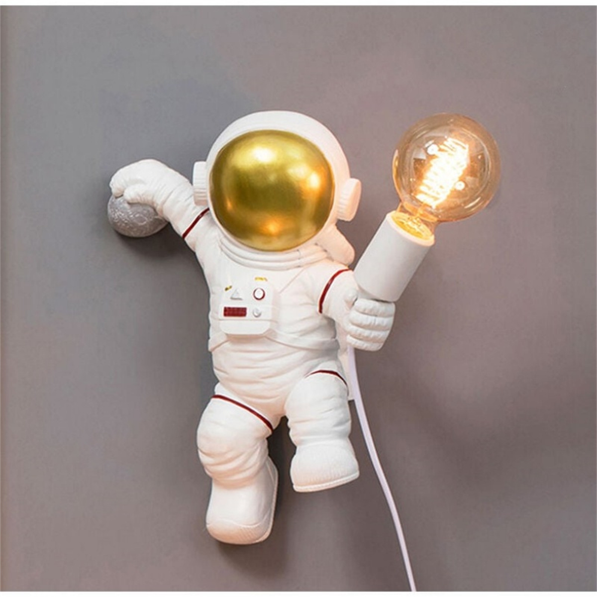 Astronautenfigur, die eine Glühbirne an einer grauen Wand hält.
