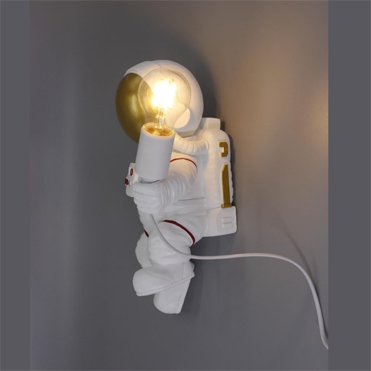 Astronauten-Wandlampe mit Glühbirne, goldenem Helm, weißem Anzug und grauem Hintergrund.