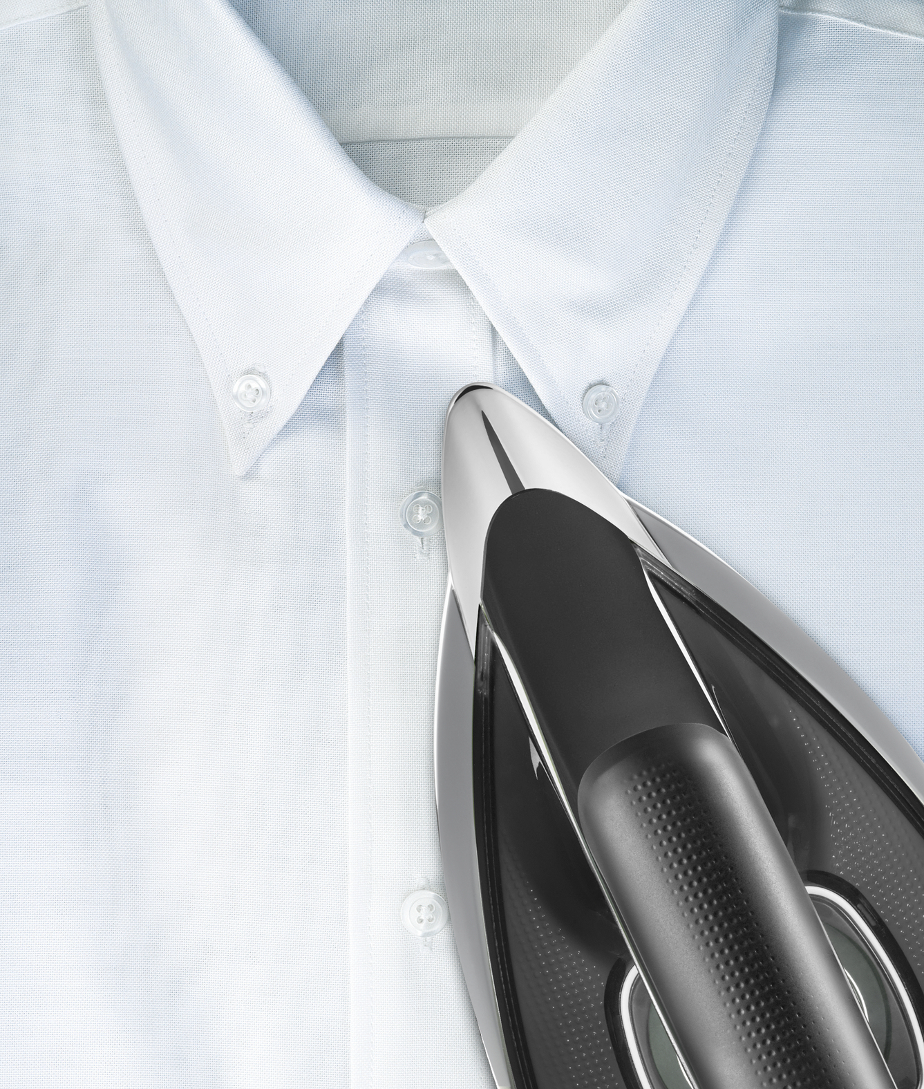 Appareil de repassage sur chemise blanche, avec poignée noire et surface brillante.