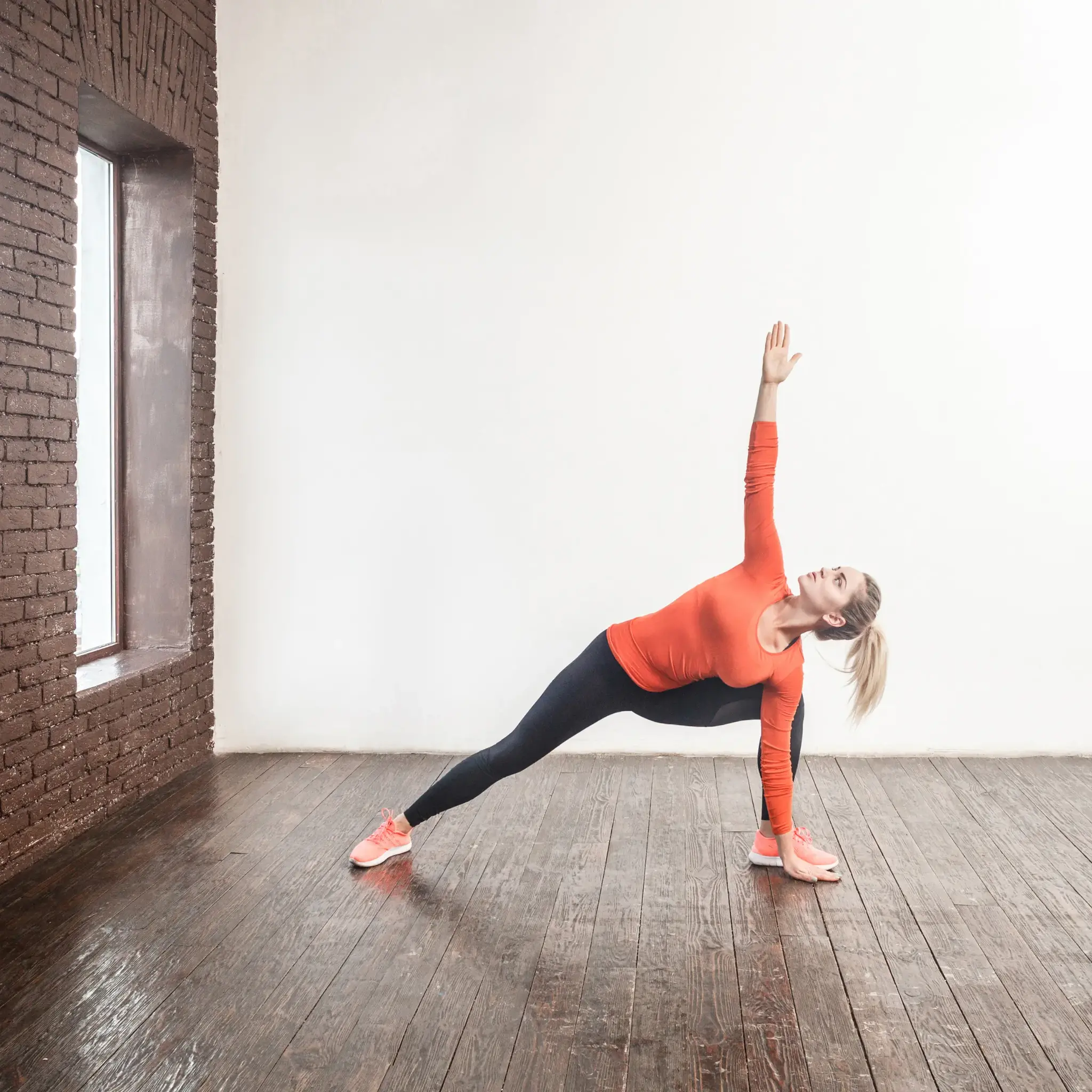 Een vrouw in sportkleding die een yogahouding doet in een studio.