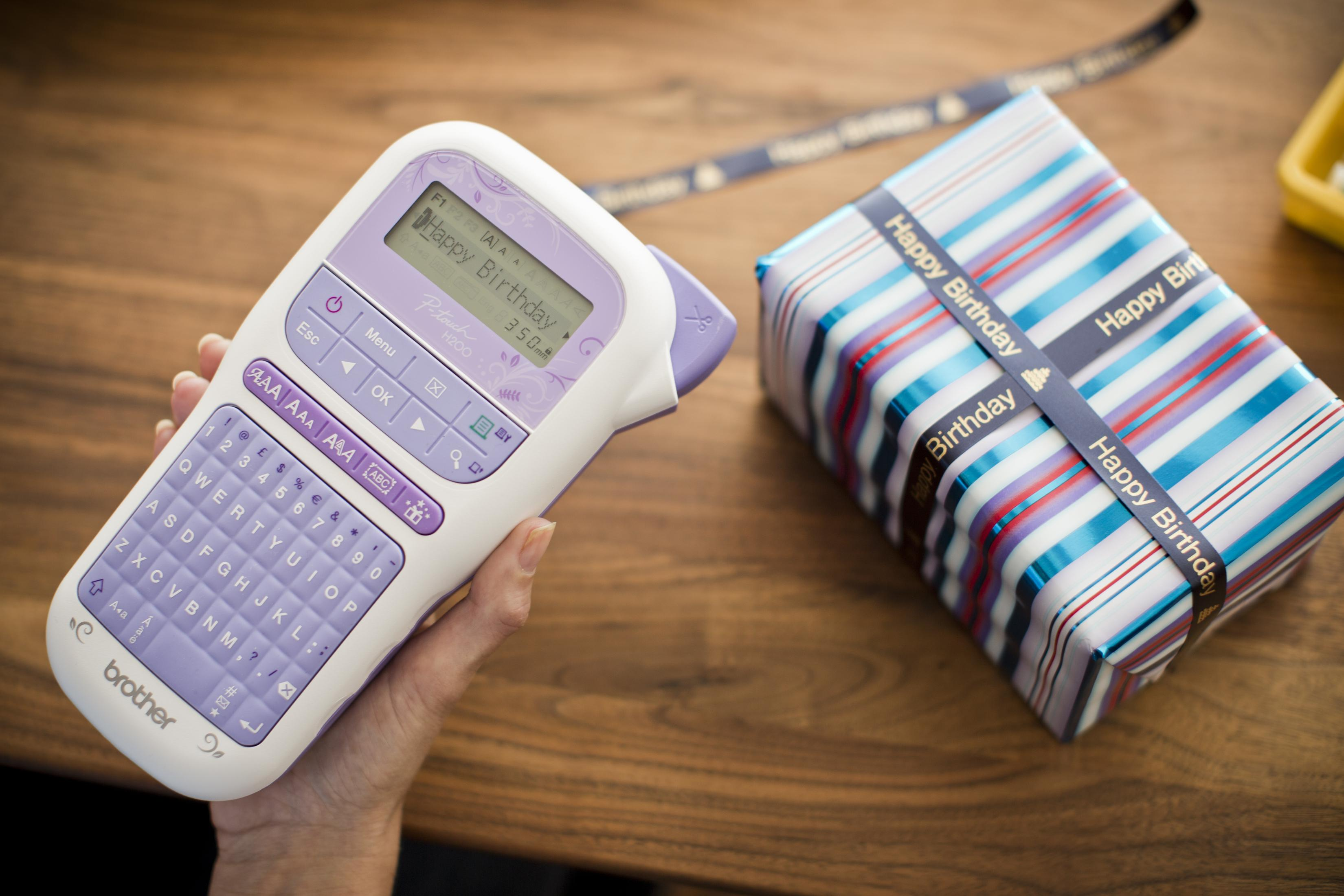 Ein Etikettendrucker und ein Geschenk, verpackt in blau-weißen Streifen mit Happy Birthday-Band.