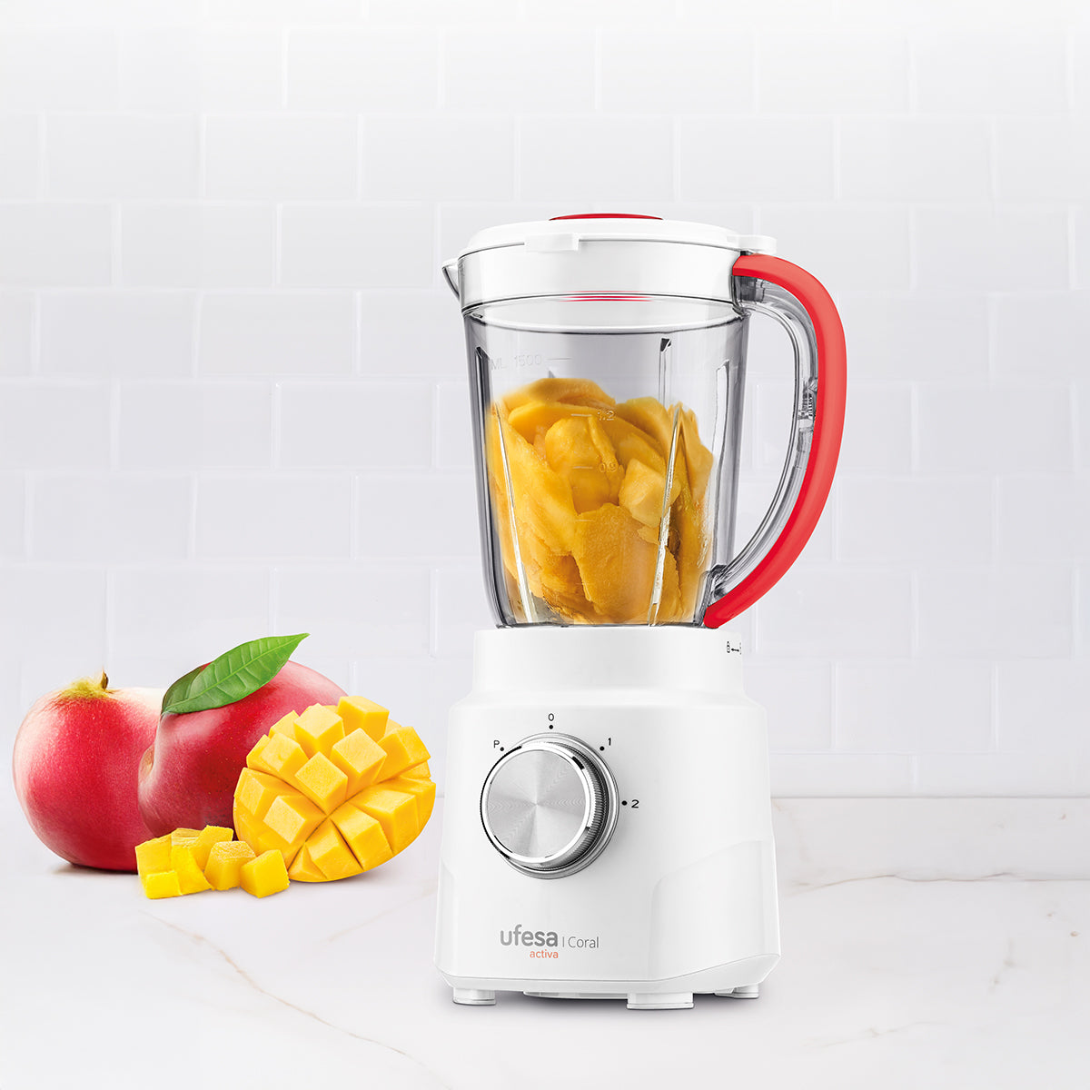 Una licuadora blanca con un tarro de vidrio con trozos de mango y dos manzanas rojas.