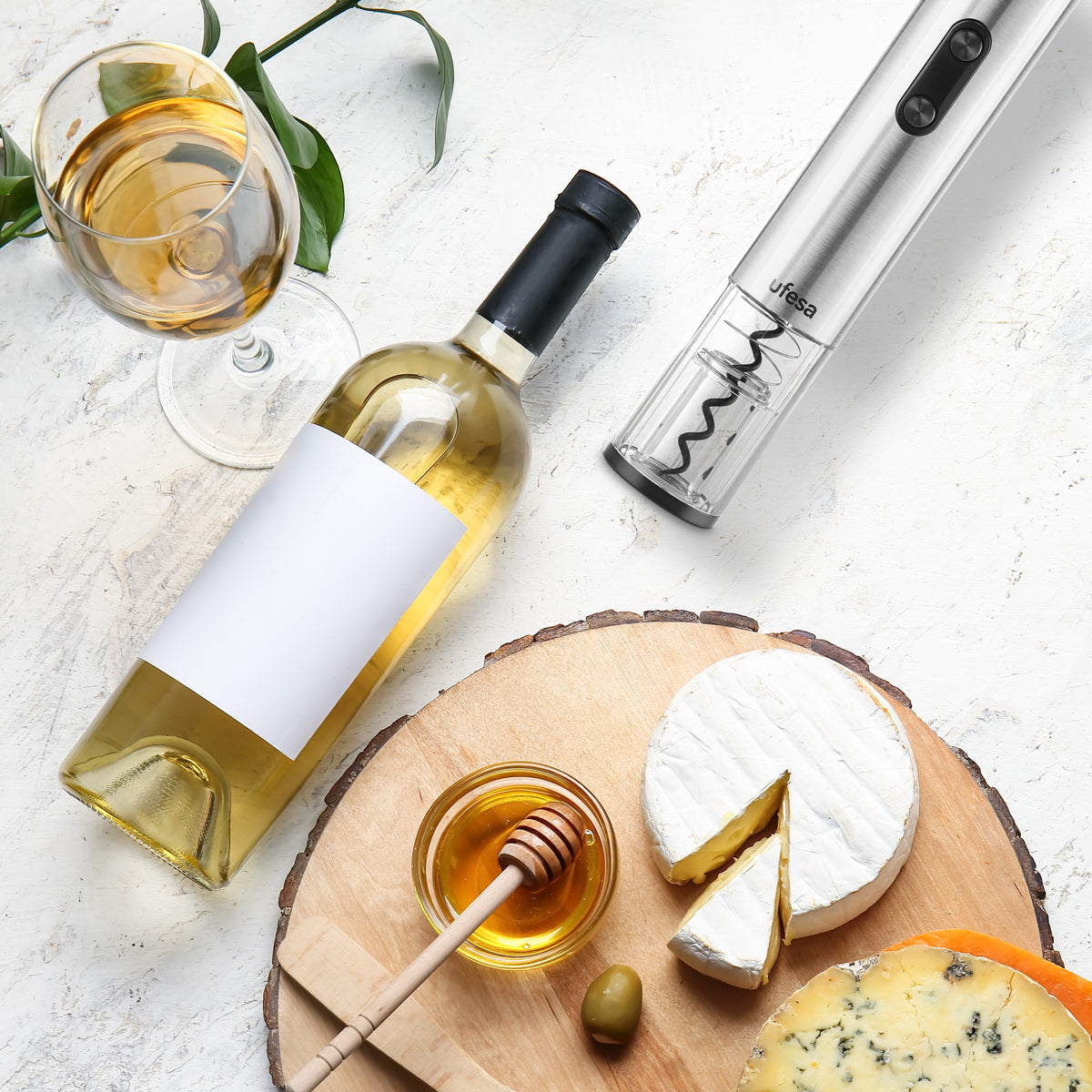 Vino, formaggio, miele e apribottiglie su un tagliere.