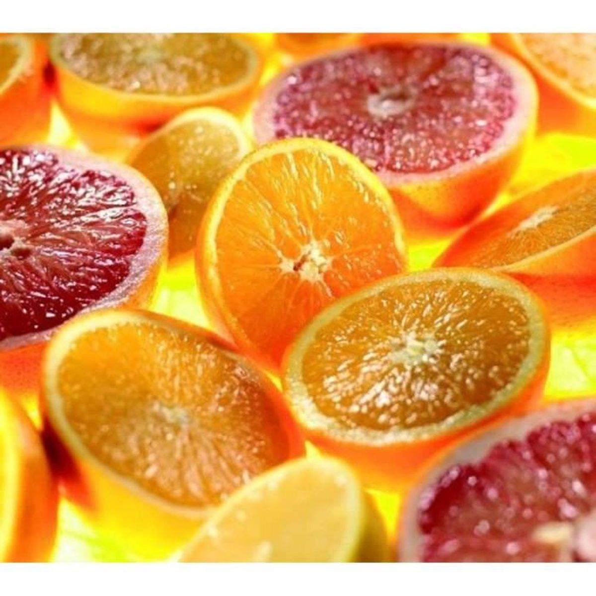 Pokrojone pomarańcze i grejpfruty w zbliżeniu, jasne żółte tło.
