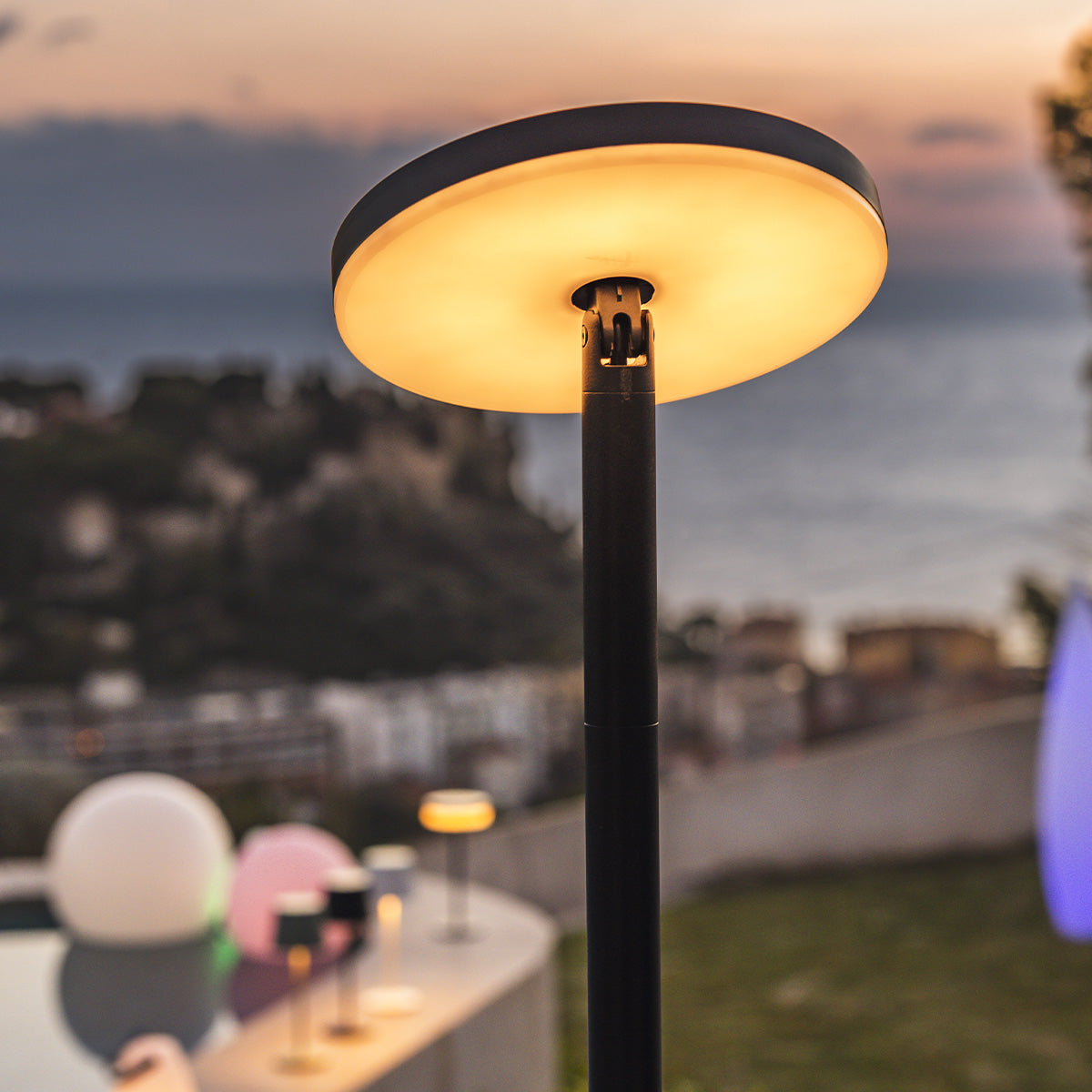 Außenlampe mit kreisförmigem Licht. Dunkler Hintergrund, andere Lichter in der Ferne.