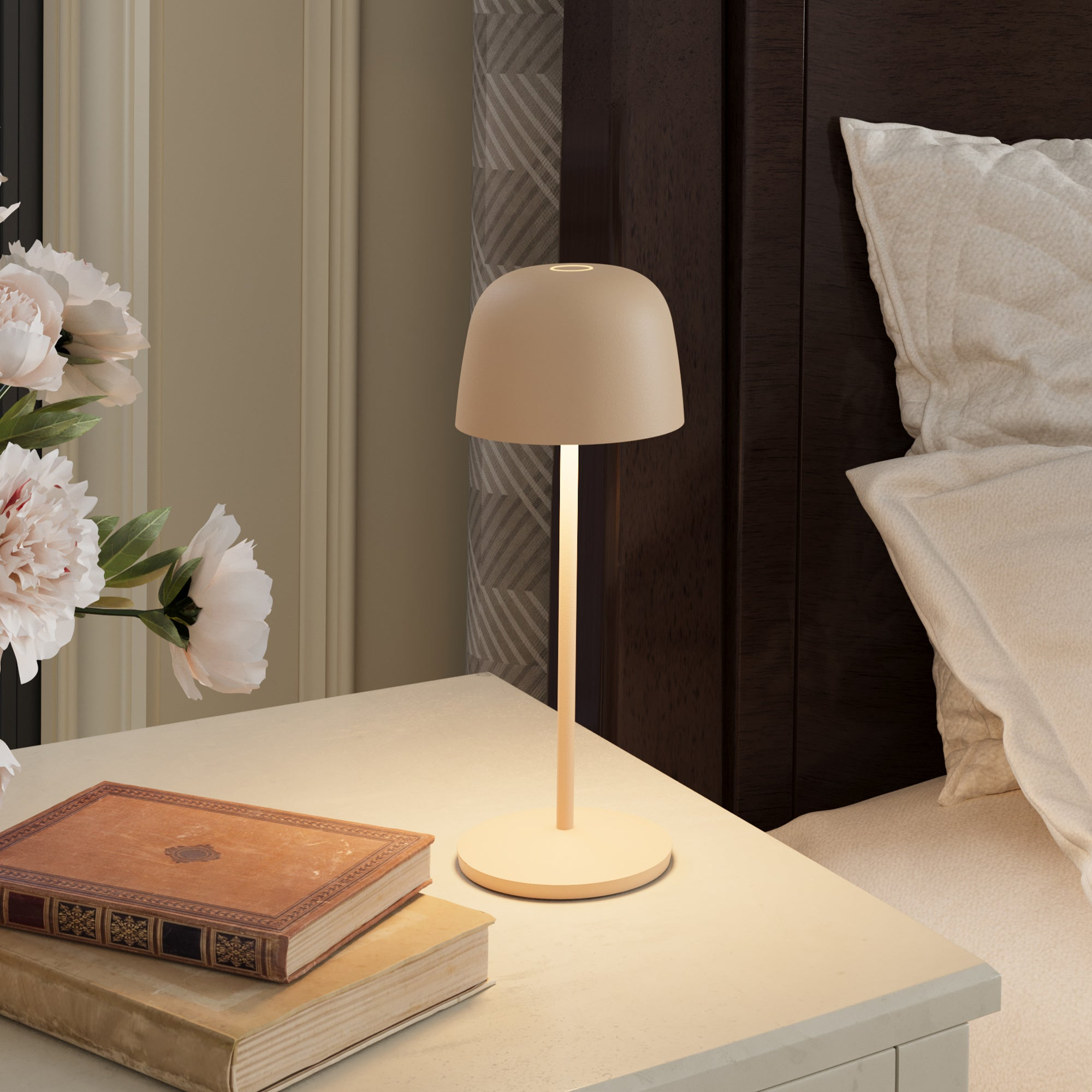 Eine beige Tischlampe mit warmem, einladendem Schein steht auf einem weißen Nachttisch.