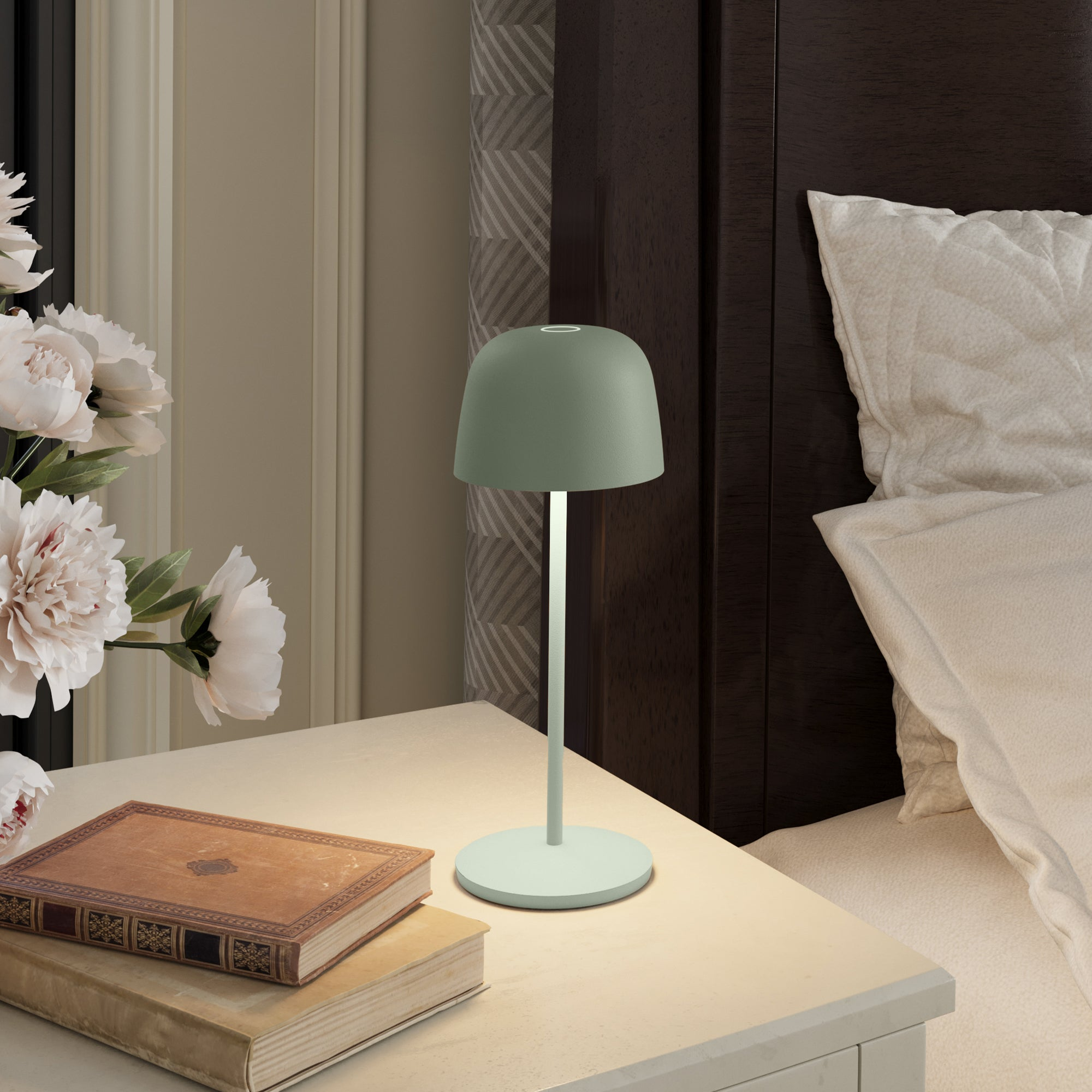 Grüne Nachttischlampe auf einem weißen Tisch mit Büchern und Blumen. Schlafzimmerumgebung.