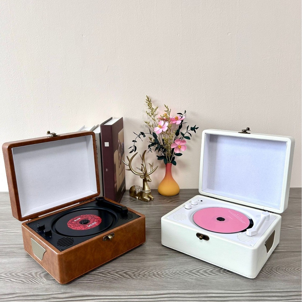Zwei Vintage-Plattenspieler, einer braun, einer weiß, mit offenen Deckeln und Dekoration.