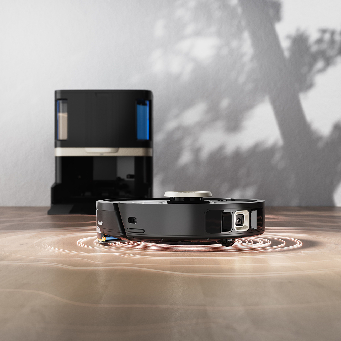 Czarny odkurzacz robot z stacją ładującą. Odkurzacz ma okrągły kształt.