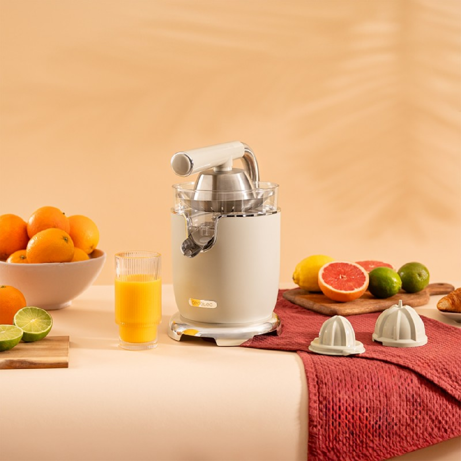 Una exprimidora con naranjas y jugo. La escena incluye un vaso de jugo y fruta en una mesa.