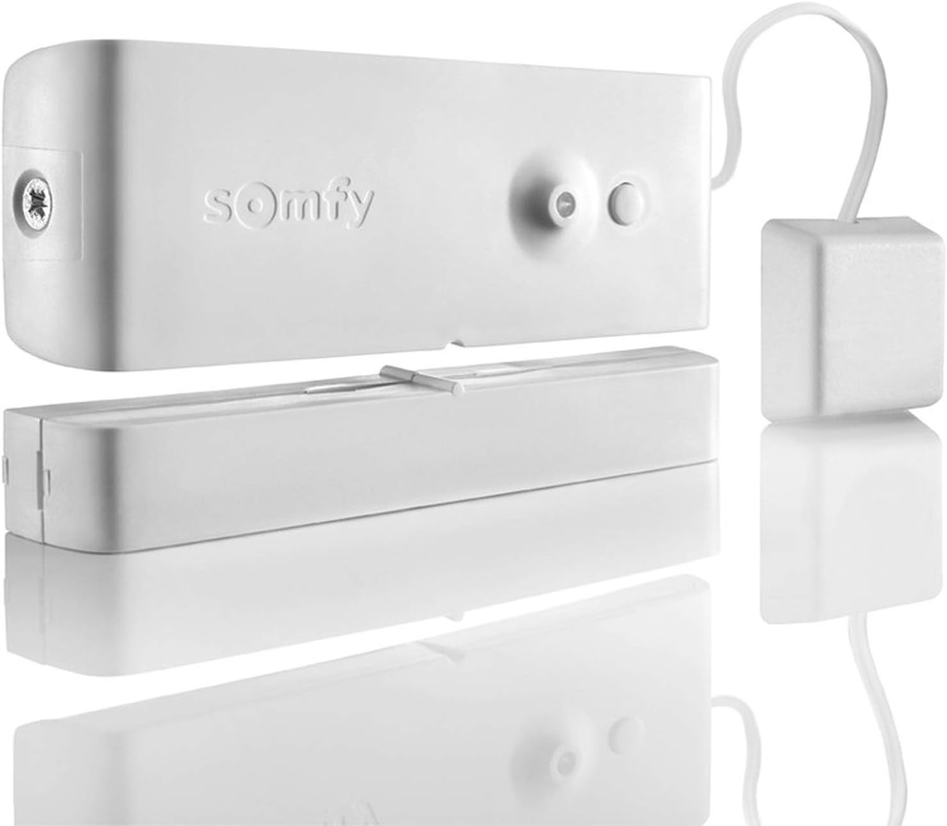 Weißes Somfy-Gerät mit einem kleinen weißen Würfel und einer Spiegelung auf weißer Oberfläche.