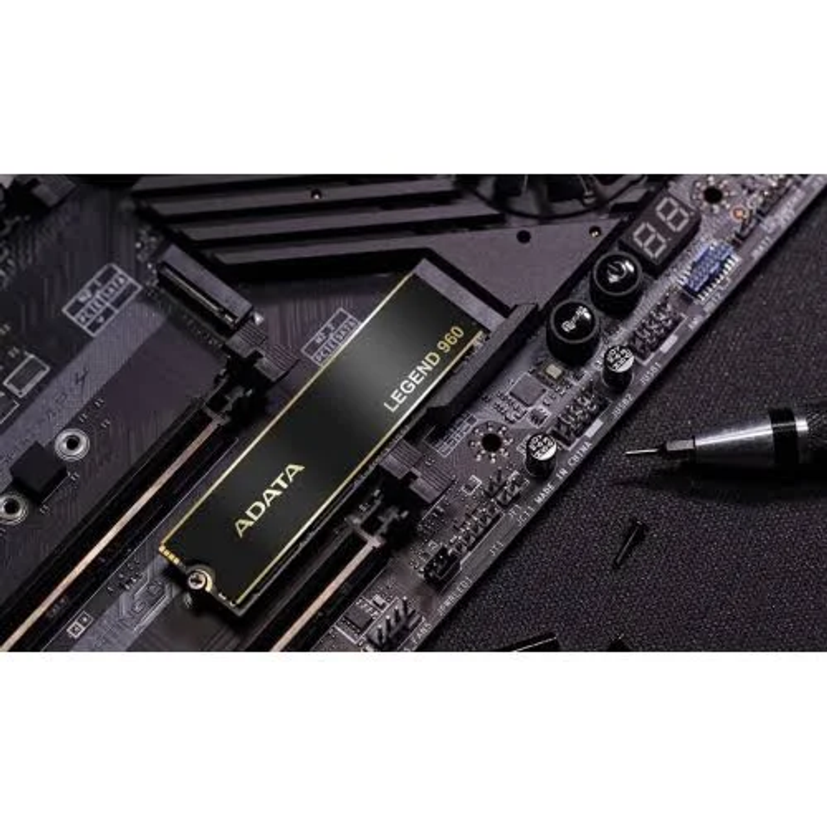 Czarny dysk SSD ADATA Legend 960 zainstalowany w płycie głównej. Widoczny śrubokręt i inne elementy.