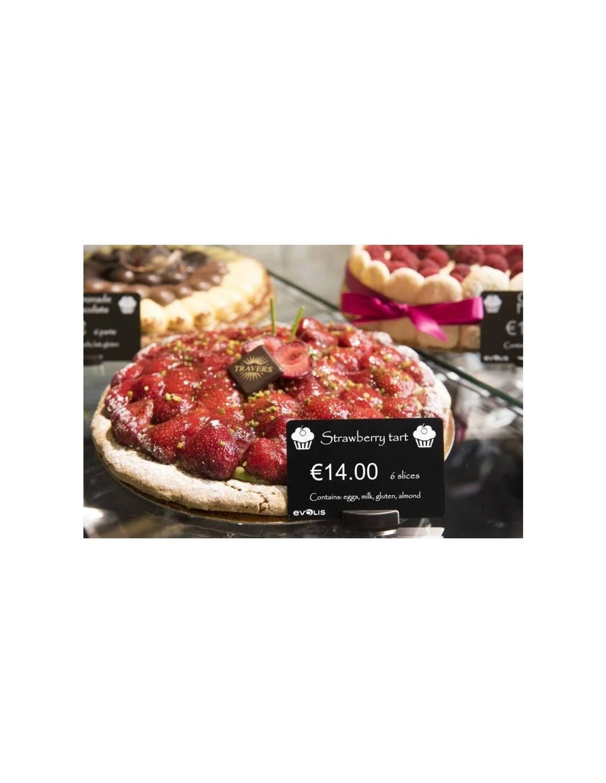 Crostata di fragole in mostra con cartellino del prezzo. Altri dessert sullo sfondo.