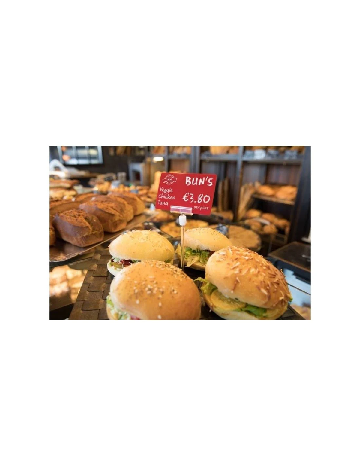 Hamburger con panini e cartellino del prezzo esposti in una panetteria.