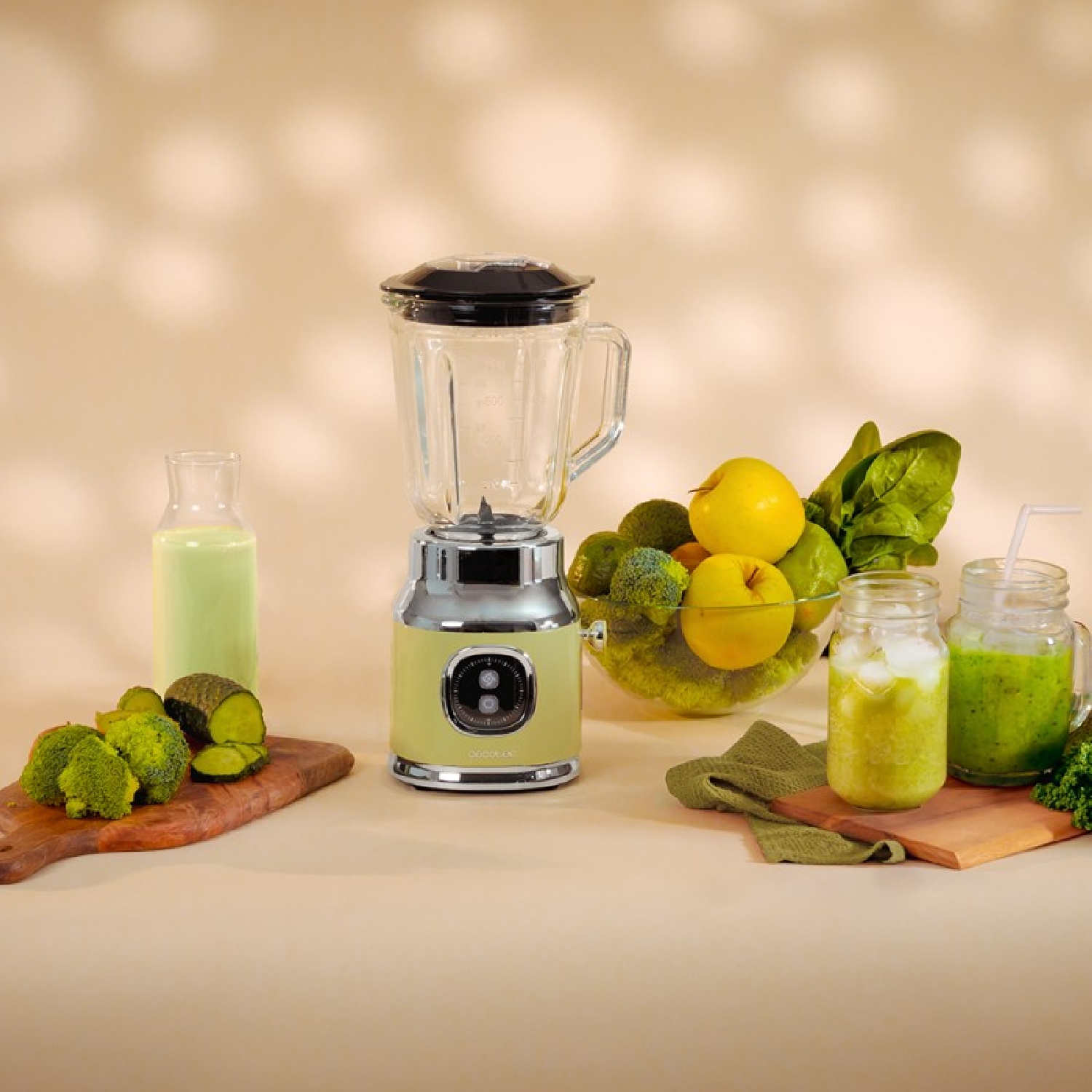 Licuadora con ingredientes: brócoli, manzanas y otras frutas. Bebidas en vasos. Tonos verdes y beige.