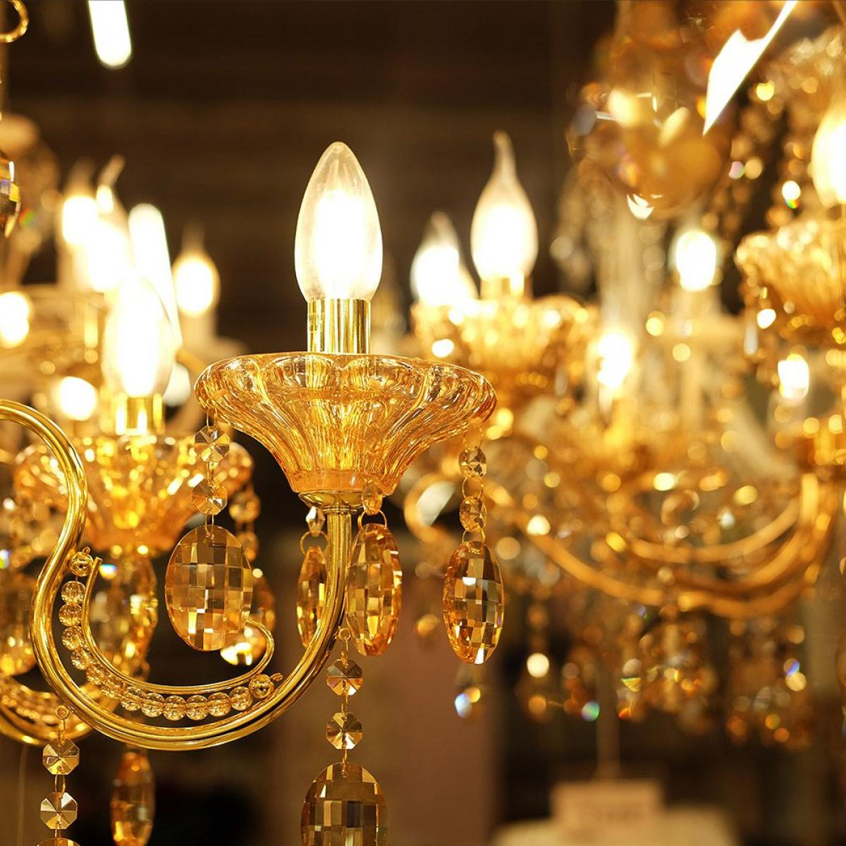 Un primo piano di un lampadario dorato ornato con lampadine accese e abbellimenti in cristallo.