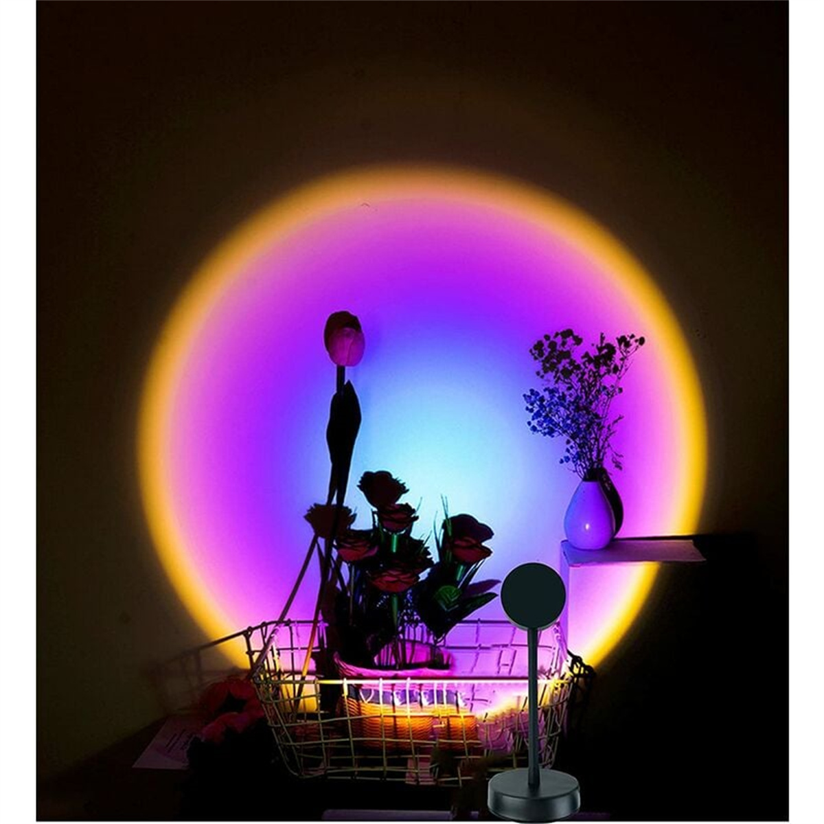 Sonnenuntergangslampe, die ein kreisförmiges Licht an die Wand projiziert, mit Blumen davor und einem kleinen Ständer.