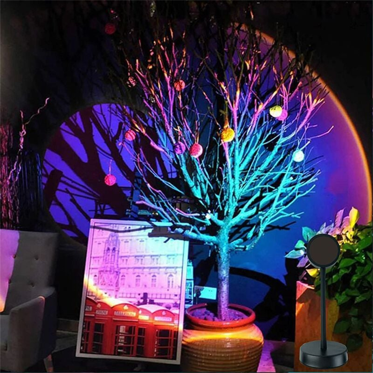 Ein beleuchteter Baum mit bunten Ornamenten, einem Bild und einer schwarzen Stehlampe.