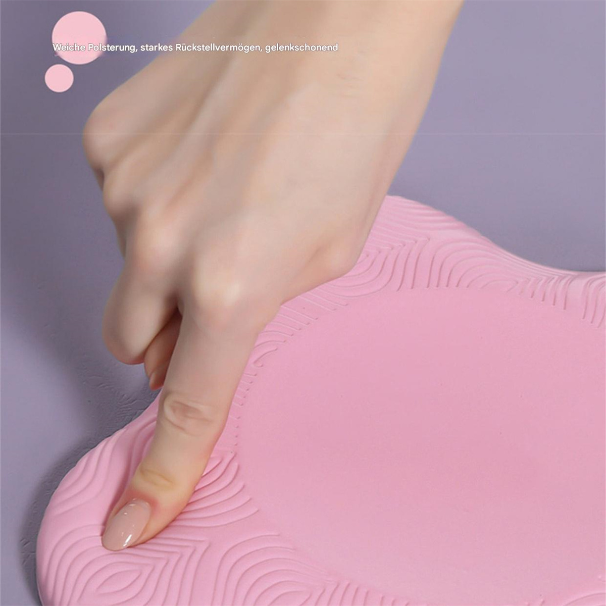 Eine Hand drückt auf die rosa Oberfläche einer Matte. Die Matte liegt auf einer lila Oberfläche.