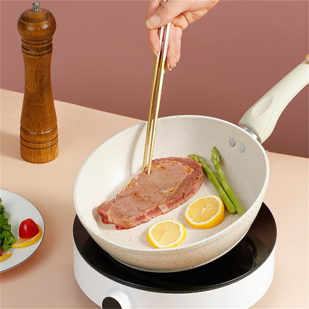 Steak in einer Pfanne mit Spargel und Zitrone, zubereitet auf einem tragbaren Kocher.