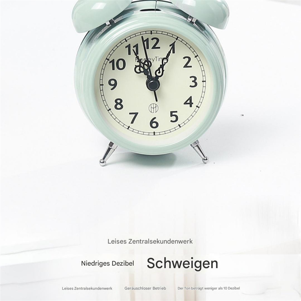 Ein mintgrüner Wecker mit weißem Zifferblatt, der die Uhrzeit anzeigt. Text auf Deutsch steht unten.