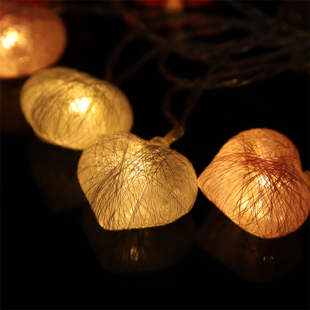 Mehrere herzförmige Lichter in dunkler Umgebung. Die Lichter sind beleuchtet und haben einen warmen Schein.