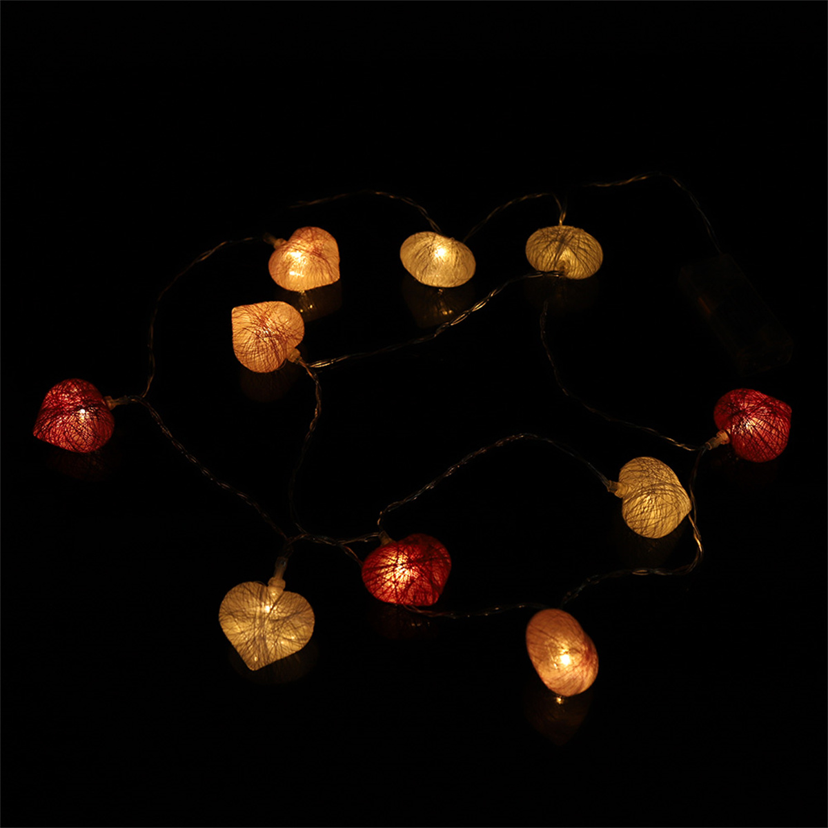 Lichterkette mit herzförmigen Lichtern. Sie sind rot, gelb und weiß und vor schwarzem Hintergrund.