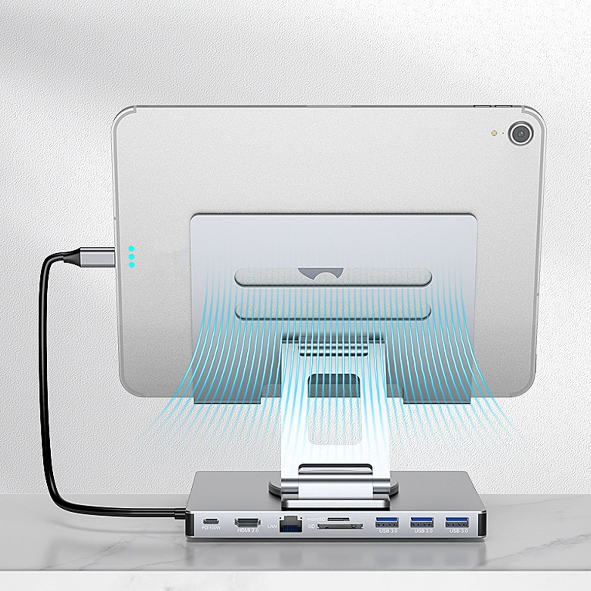 Ein Tablet steht in einem silbernen Ständer und ist mit einem USB-Hub verbunden. Blaue Linien illustrieren den Luftstrom vom Ständer.