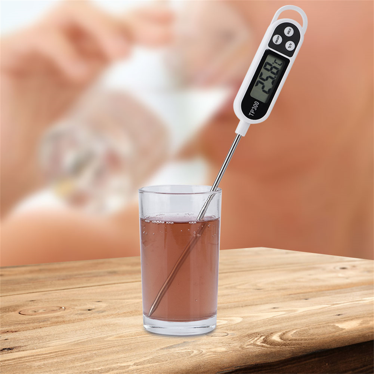 Thermometer in einem Glas Wasser. Digitalanzeige zeigt 25,8 Grad. Verschwommener Hintergrund.