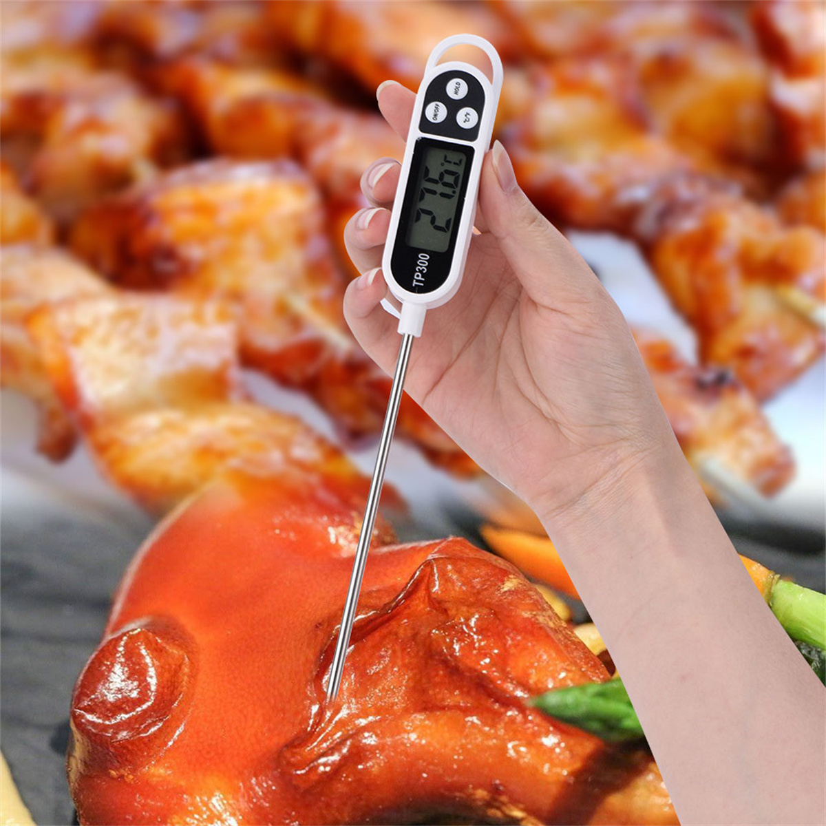 Eine Hand hält ein Thermometer, das die Fleischtemperatur misst, im Hintergrund gekochtes Fleisch und Gemüse.