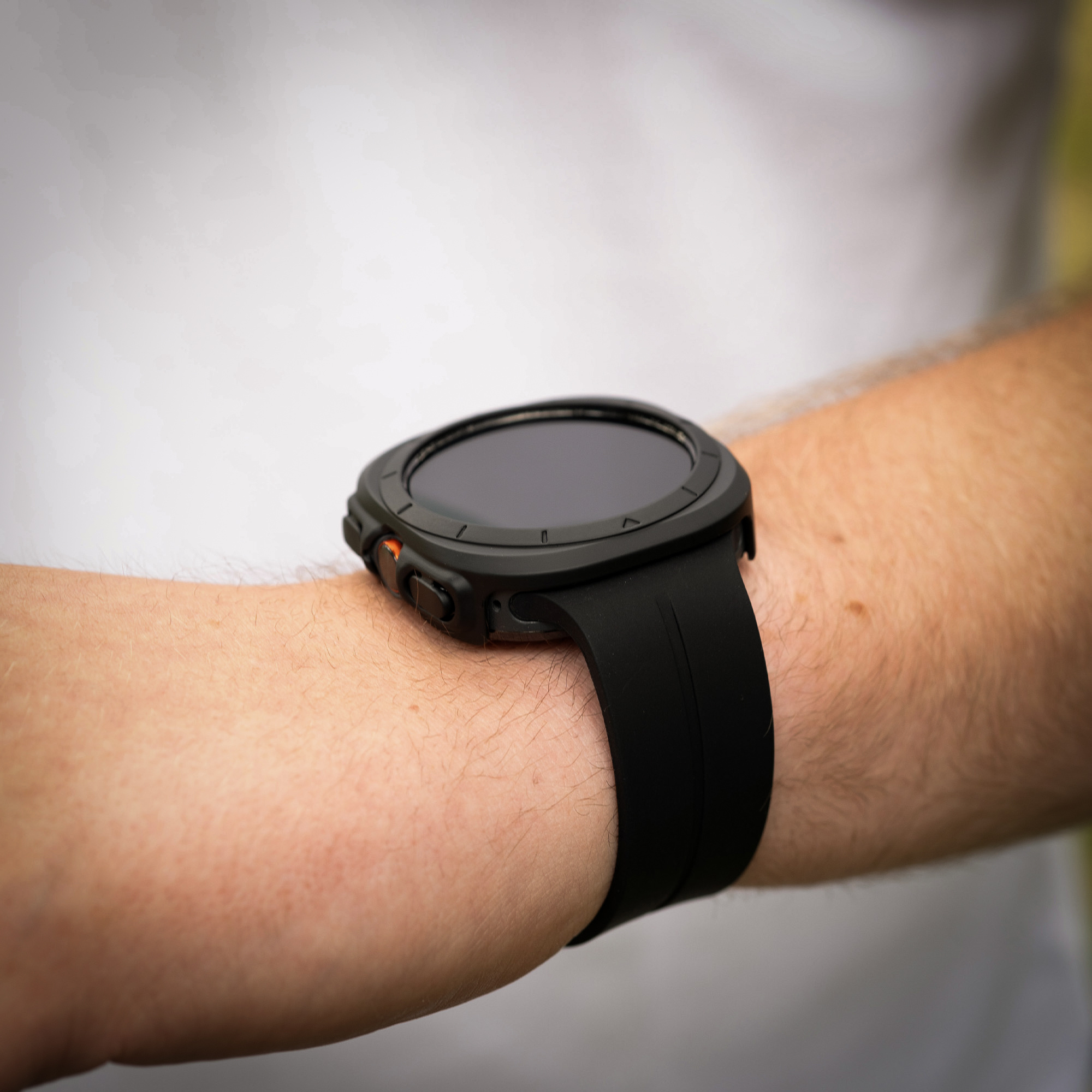 Schwarze Smartwatch am Handgelenk. Zeigt die Zeit und hat Seitentasten.