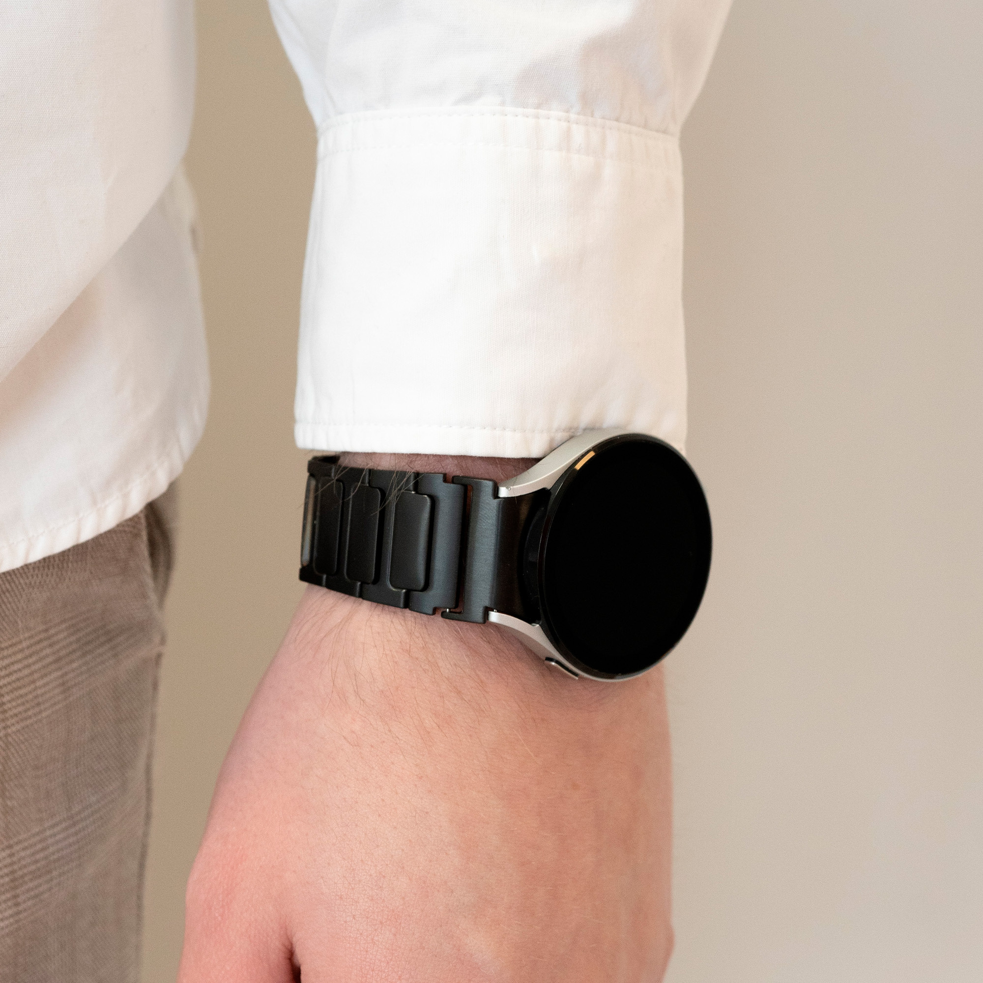 Der Arm einer Person mit einer Smartwatch. Die Uhr ist schwarz und das Armband ist aus Metall.
