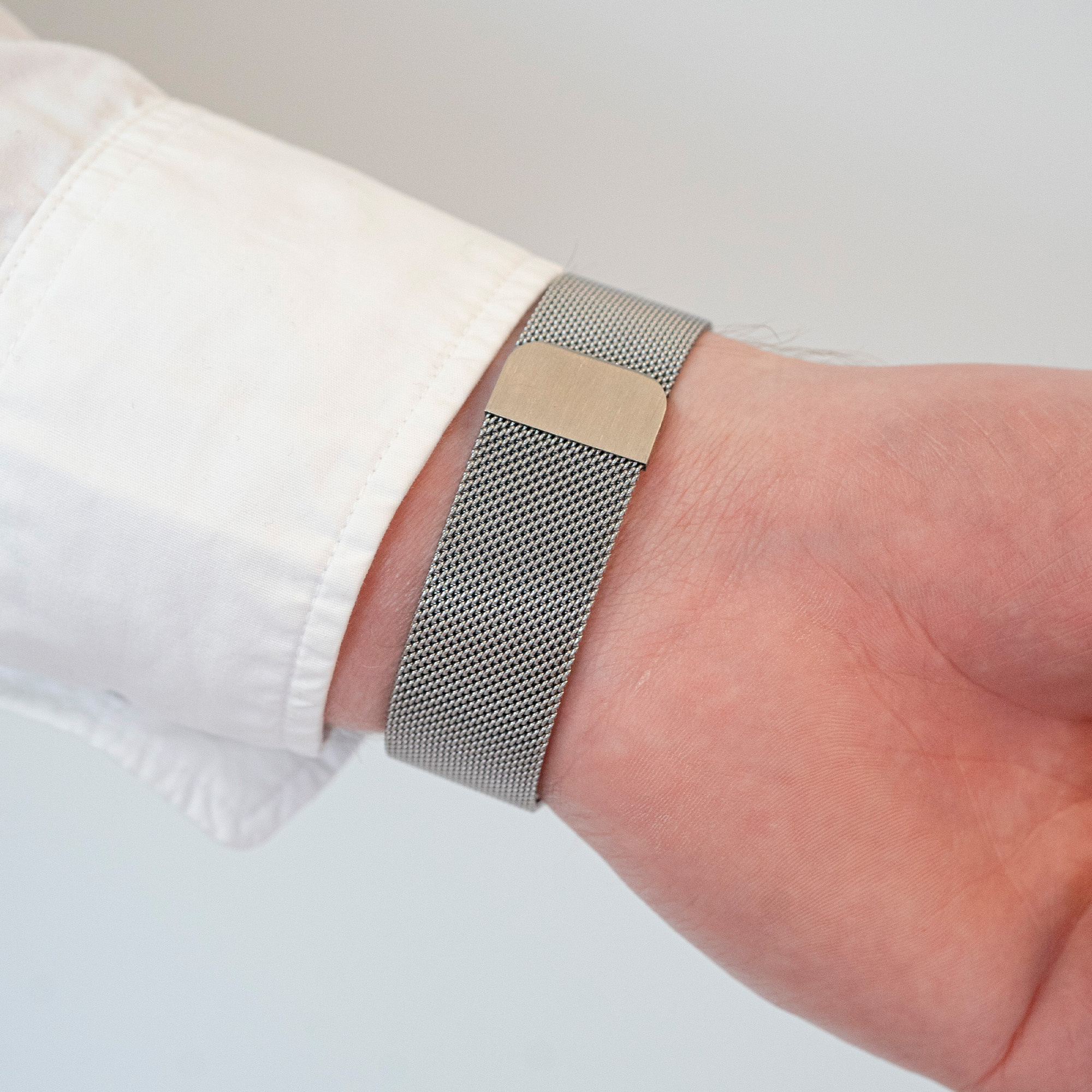 Eine Person, die eine Smartwatch mit einem silbernen Mesh-Armband trägt.