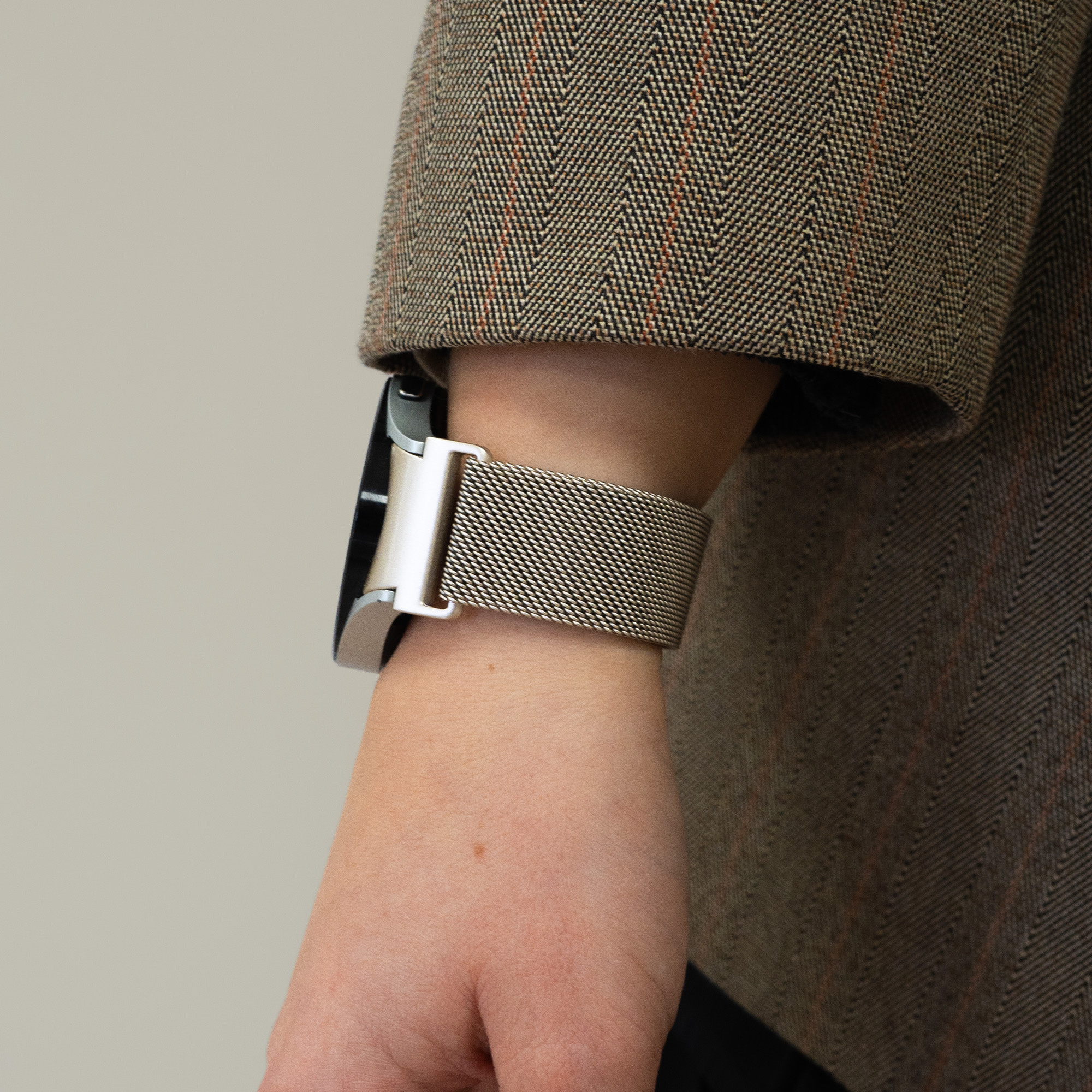 Nahaufnahme eines Handgelenks mit einer Uhr mit Metallmaschenband. Neutraler Hintergrund.