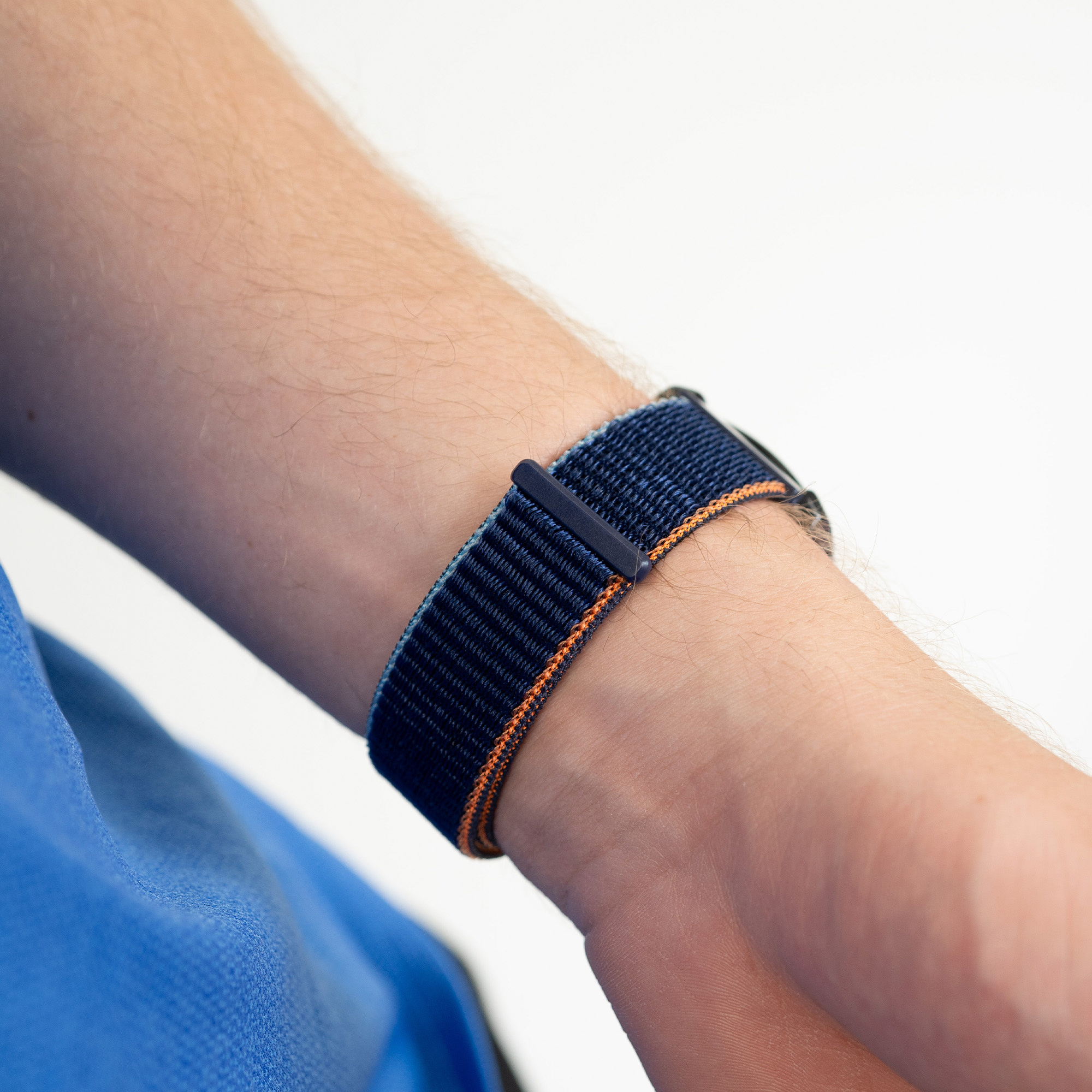 Ein Handgelenk mit einem marineblau-orange gestreiften Uhrenarmband mit schwarzer Schnalle.