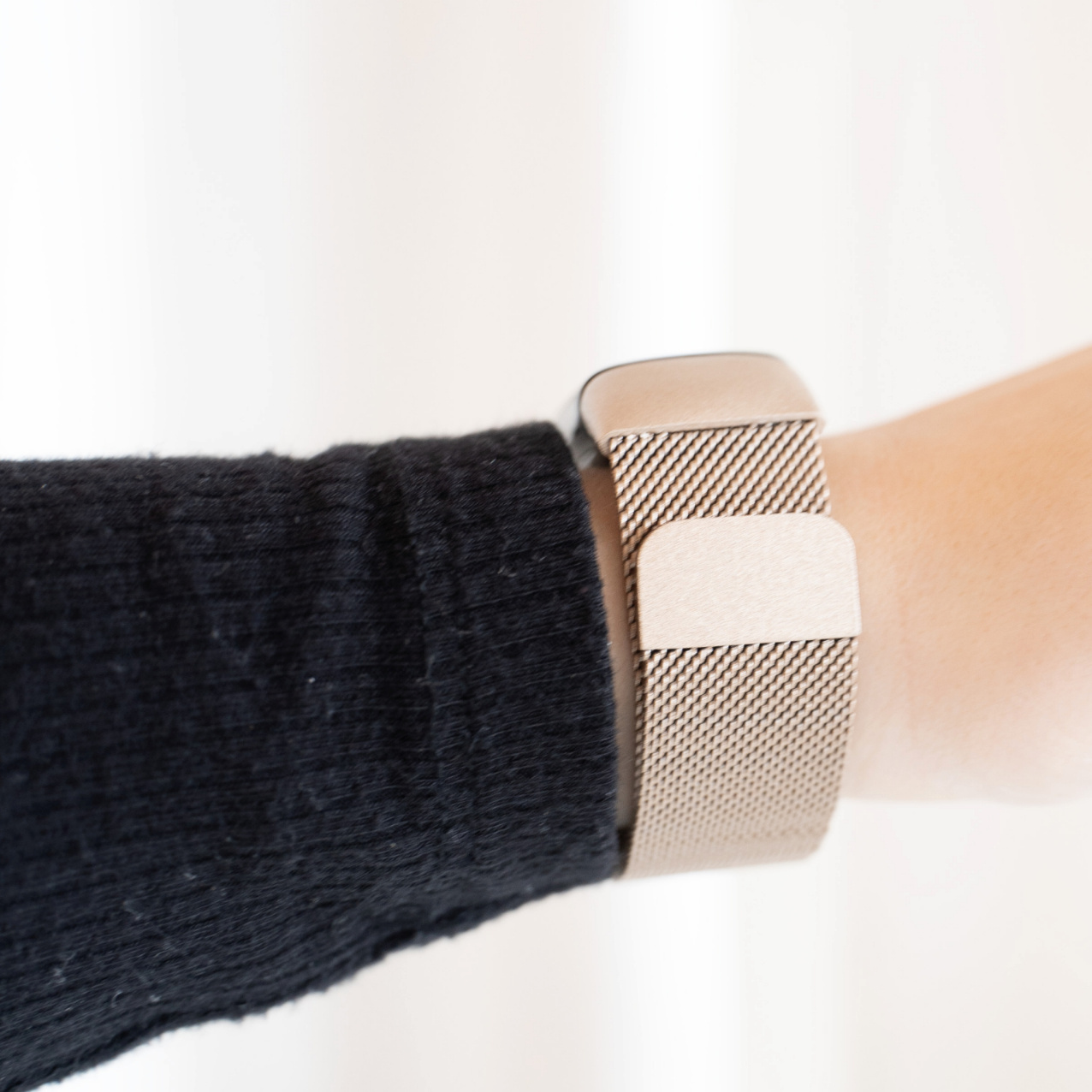 Nahaufnahme eines Handgelenks mit einem Mesh-Metall-Armband. Schwarzes Langarmshirt.
