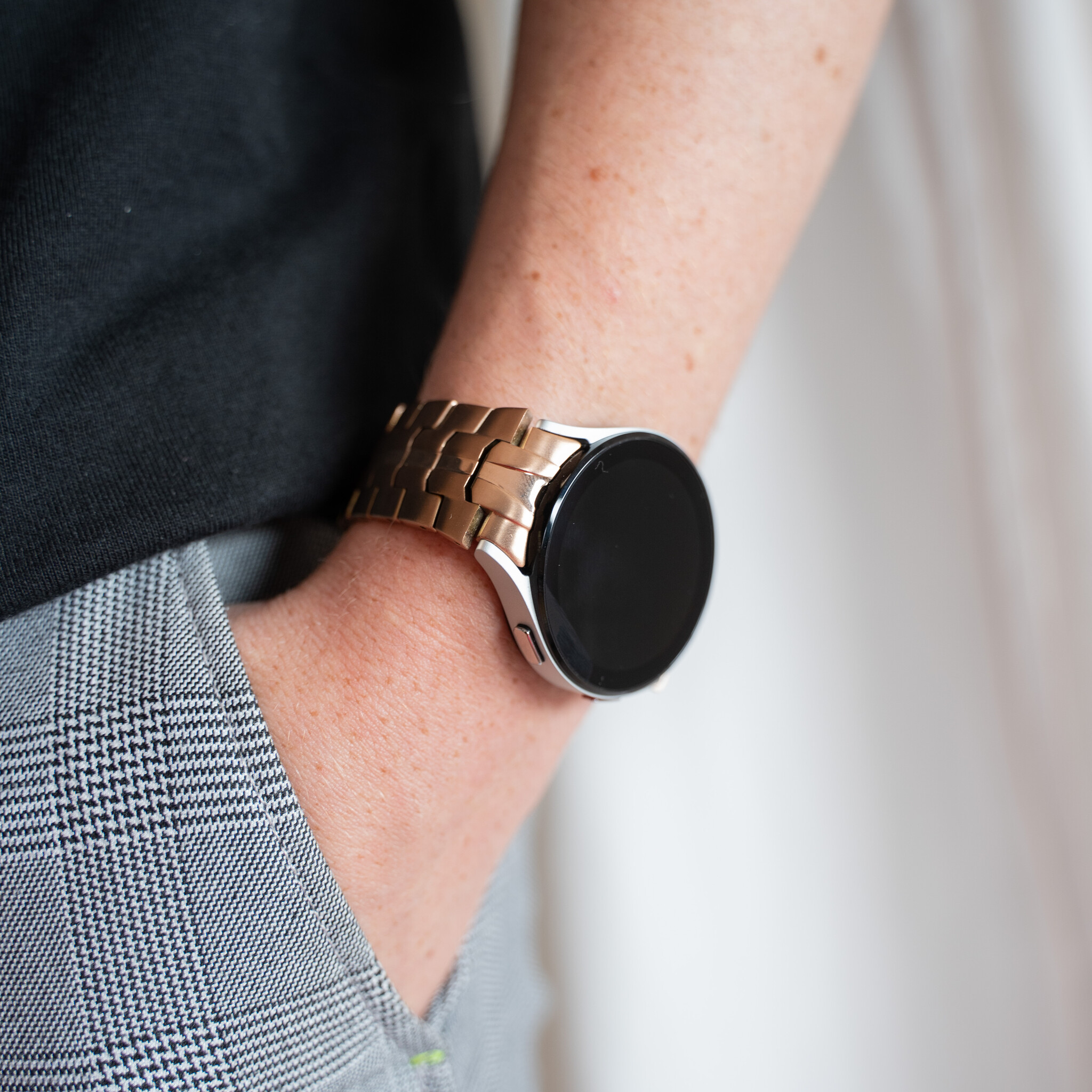 Nahaufnahme eines Handgelenks mit einer roségoldenen Smartwatch mit schwarzem Bildschirm.