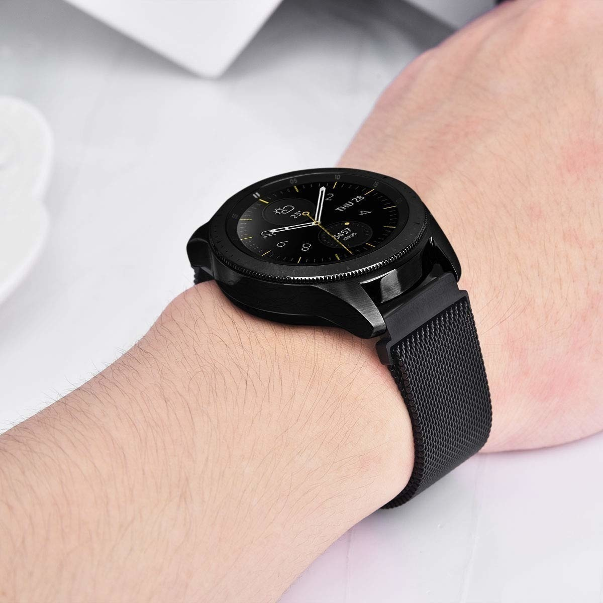 Schwarze Uhr am Handgelenk mit schwarzem Mesh-Armband.