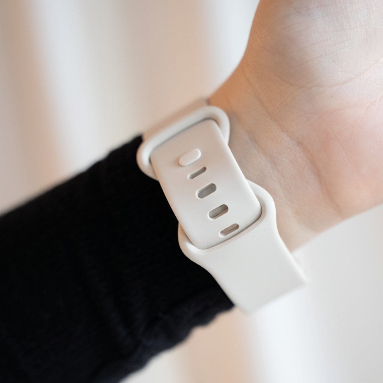 Handgelenk mit einem weißen Uhrenarmband. Das Band ist hell und mit dem Uhrengehäuse verbunden.