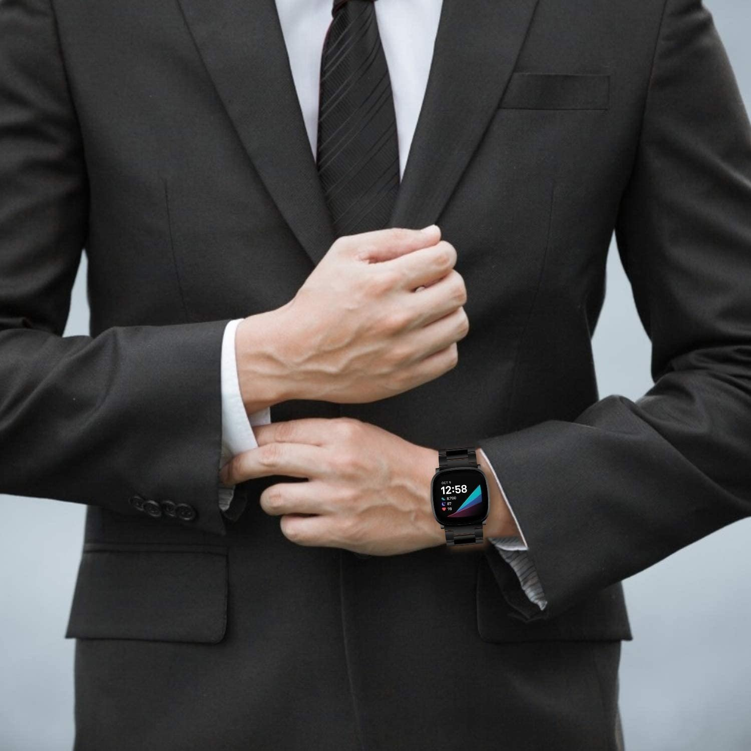 Ein Mann im Anzug trägt eine schwarze Smartwatch. Die Uhr zeigt die Uhrzeit an.