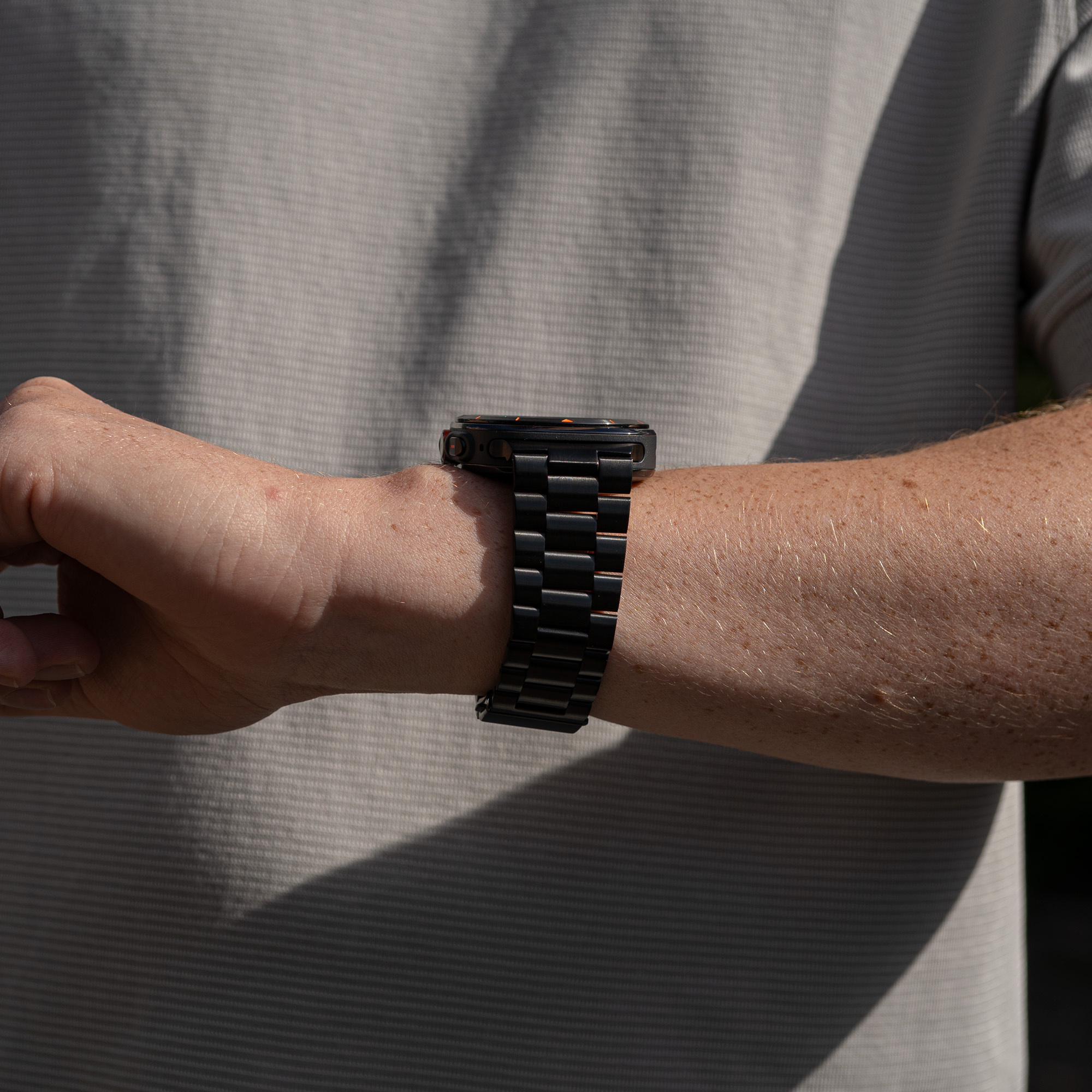 Eine Person, die eine schwarze Uhr mit einem schwarz-orangenen Armband trägt.