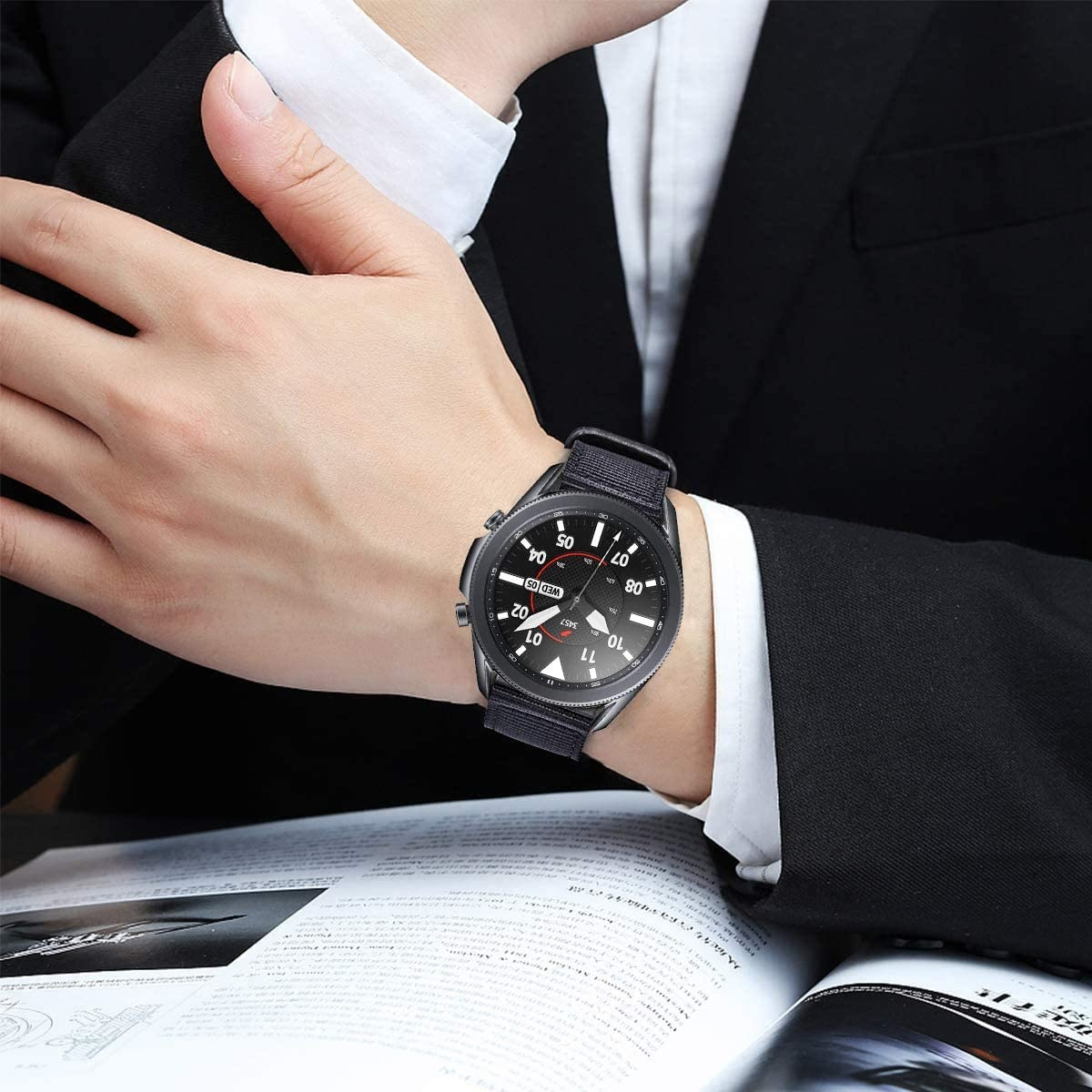 Handgelenk eines Mannes mit schwarzer Smartwatch, liest ein Buch. Schwarzer Anzug.